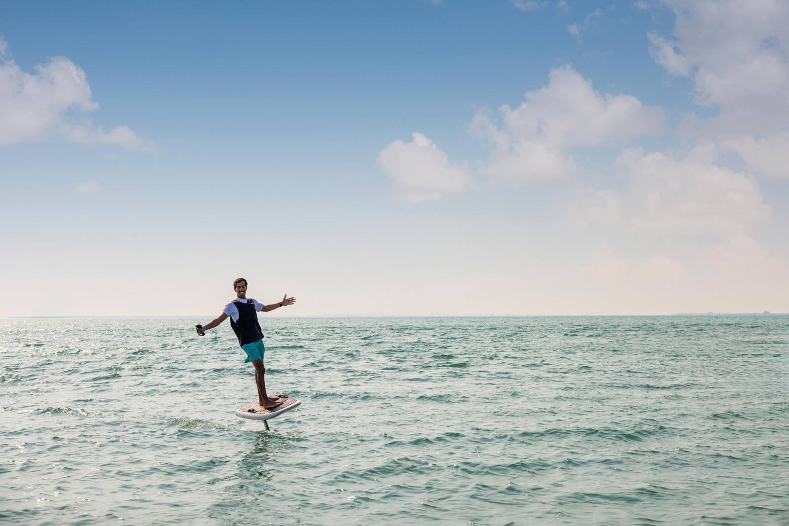 Surfer riding waves with blue sky and white clouds in the background