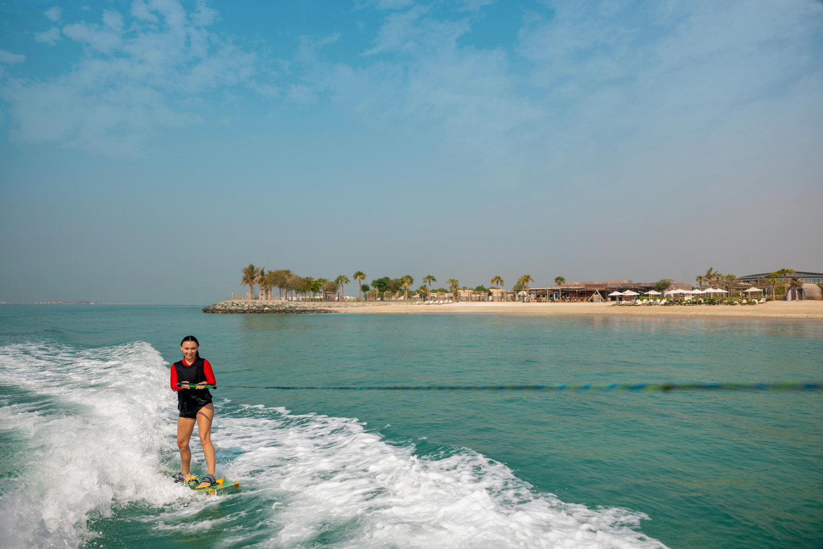 Surfer on water with trees and sky in background. Emirati speedboat activities