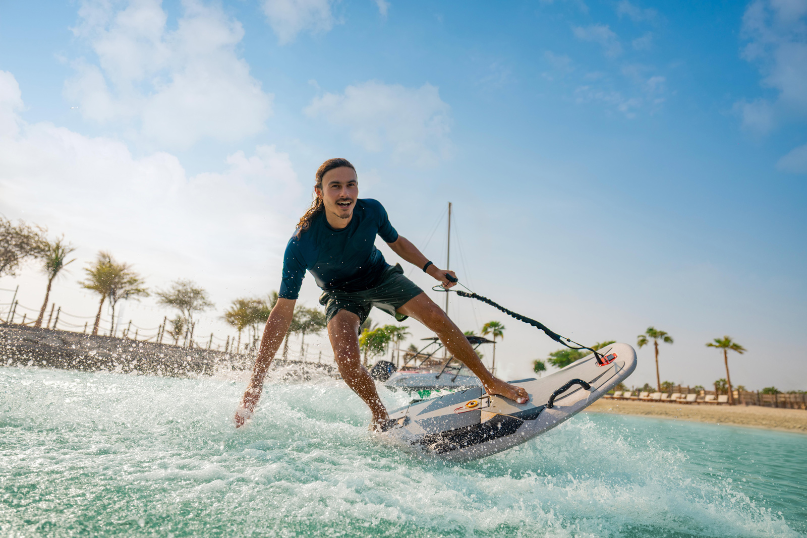 Surfer riding waves on the water with trees and sky in the background. Surfing in Abu Dhabi