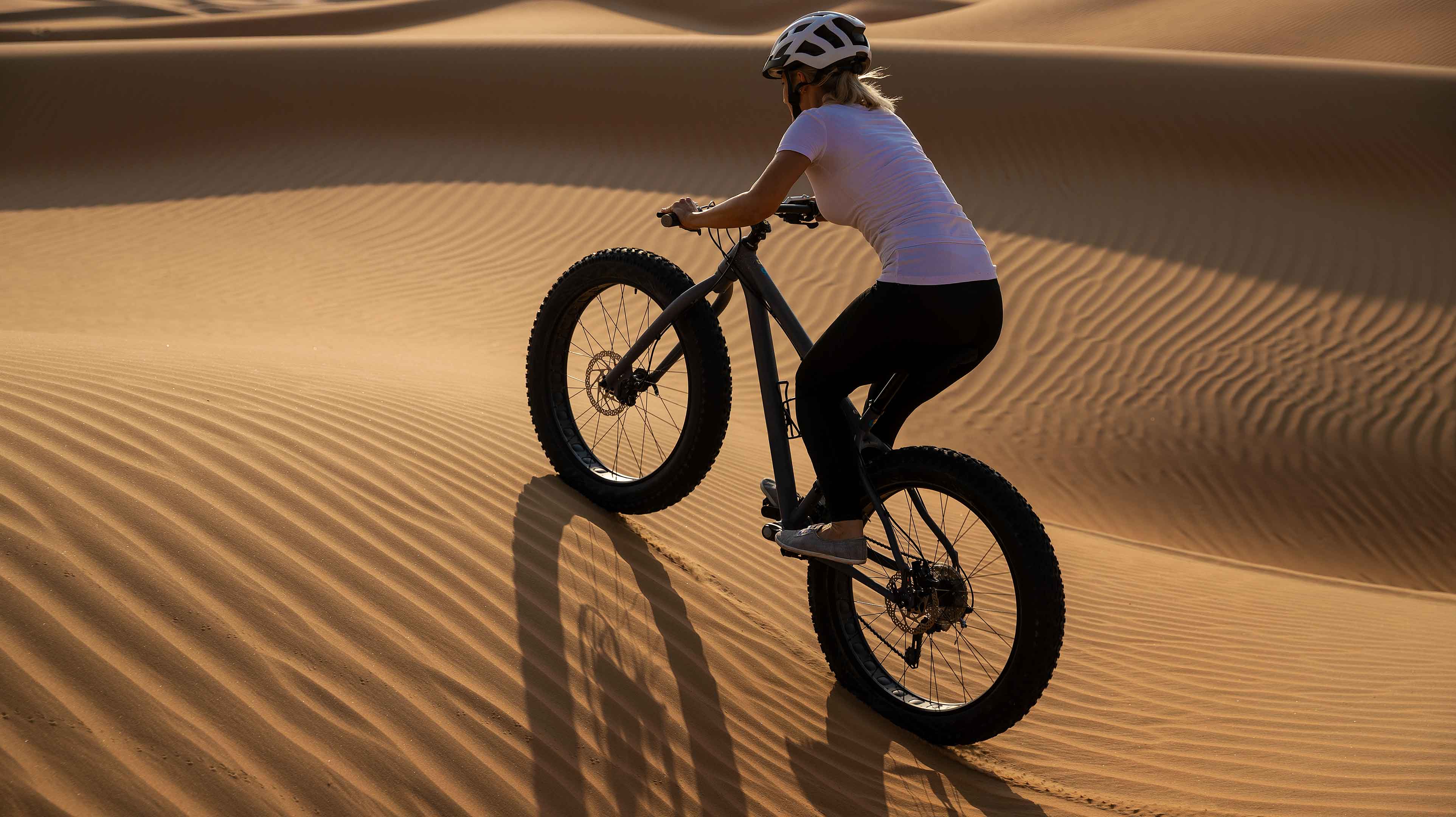 امرأة تقوم بركوب الدراجة الهوائية في صحراء أبوظبي