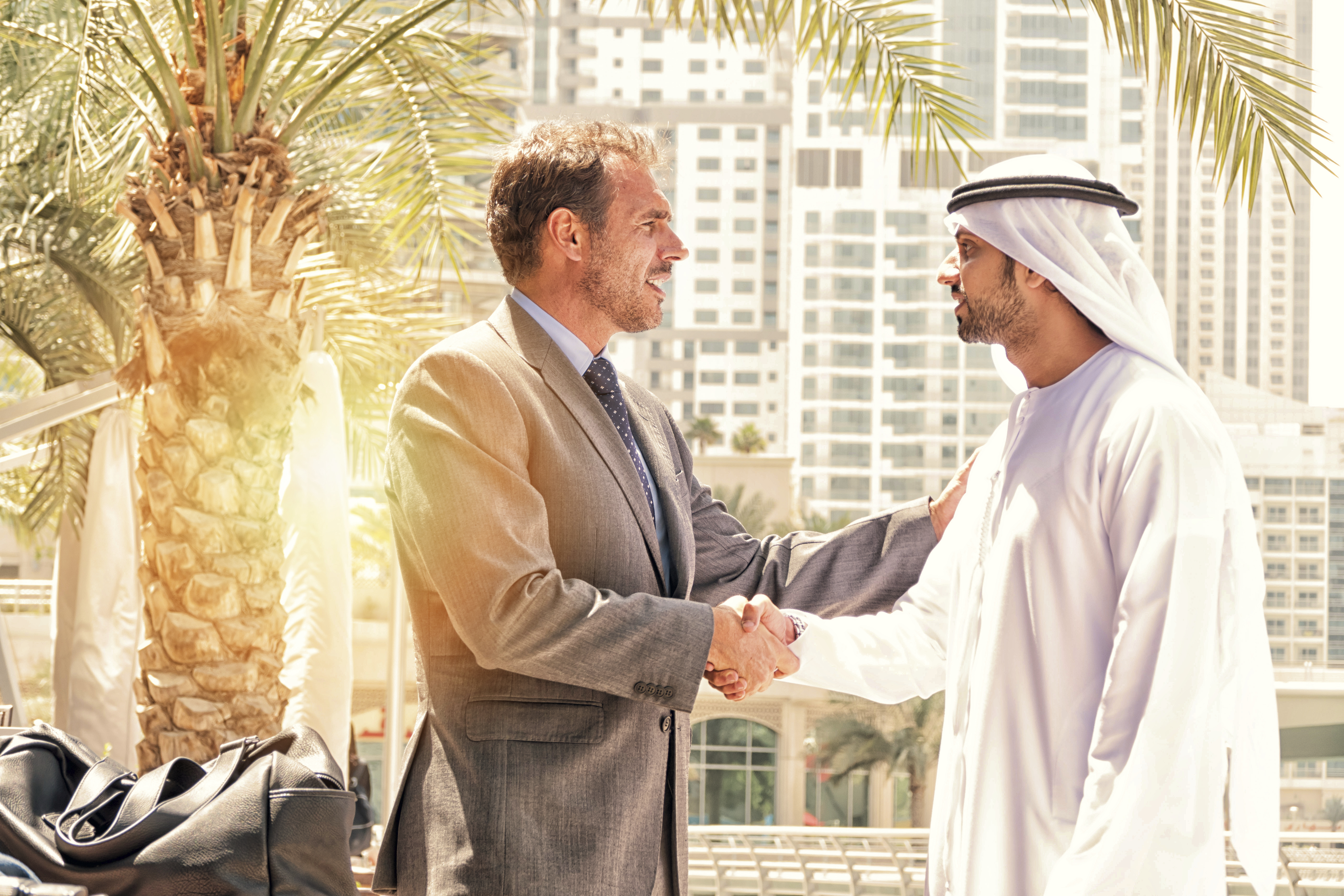 Two Emirati and Western businessmen discussing working together as part of the Agency Reward Scheme