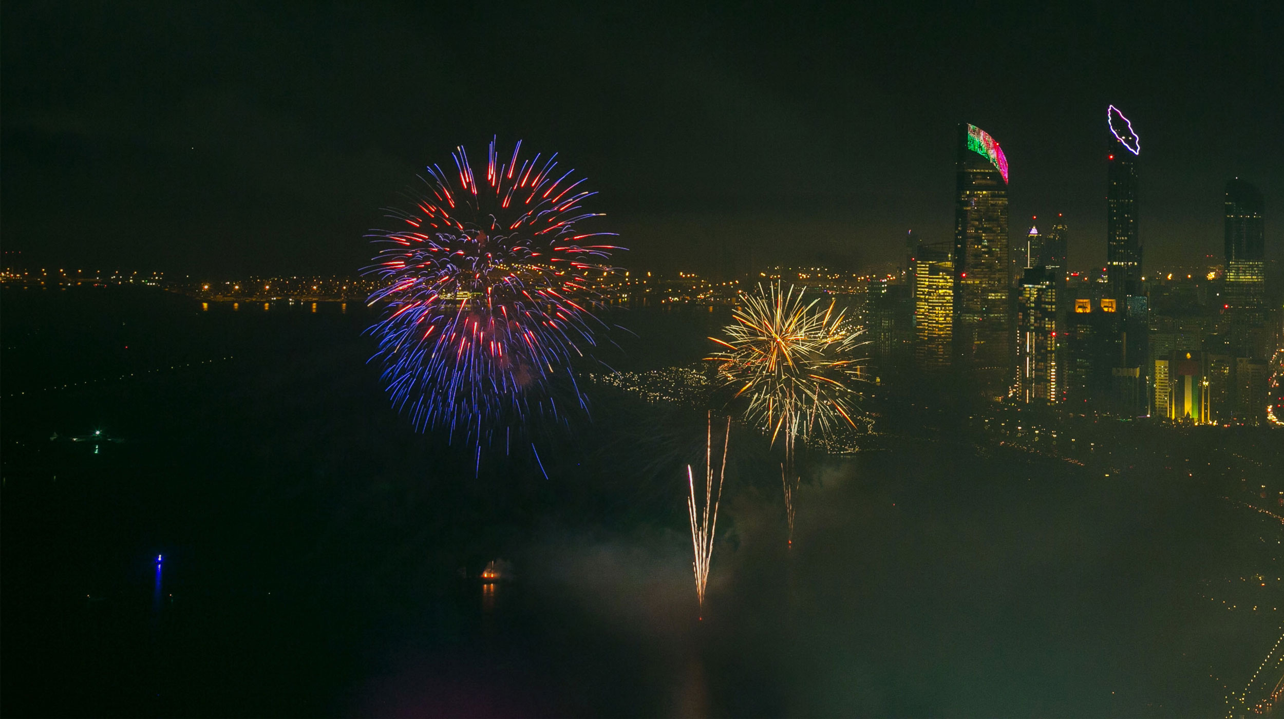 Colorful fireworks light up the night sky above Abu Dhabi city skyline during a festive celebration.