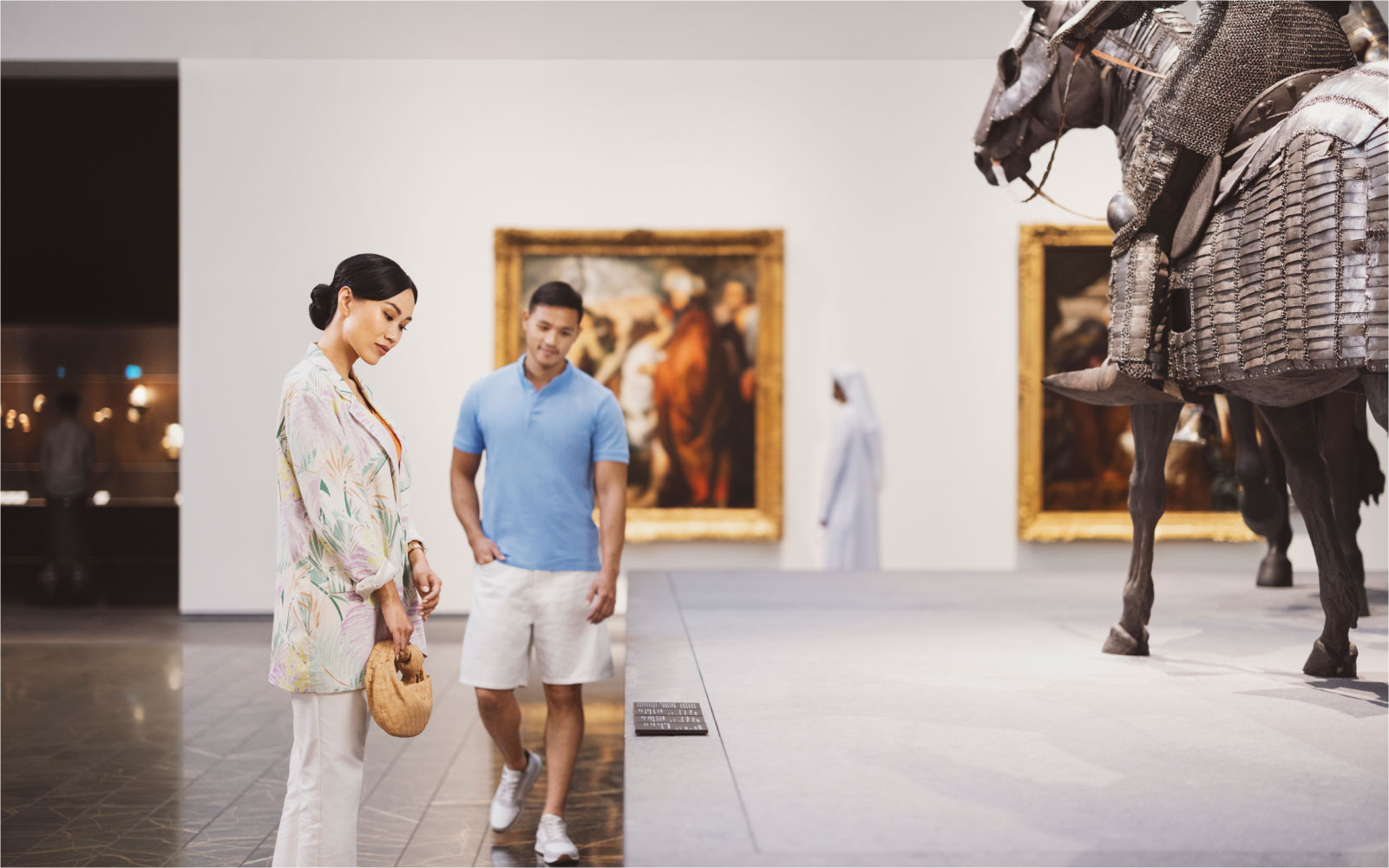 Couple admiring historical exhibits and artwork in a museum gallery in Abu Dhabi.