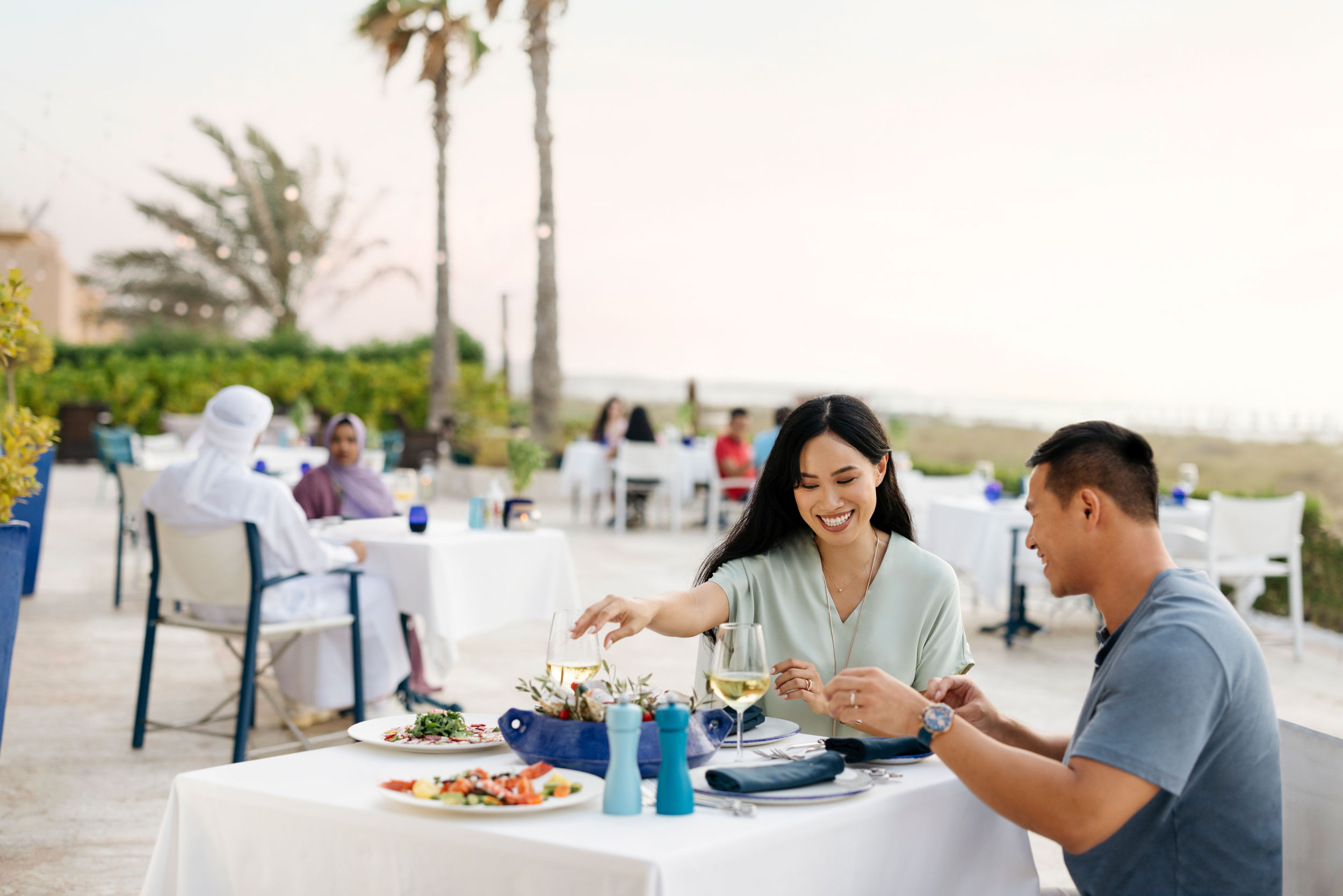 Couple enjoying a romantic outdoor dining experience by the beach in Abu Dhabi.