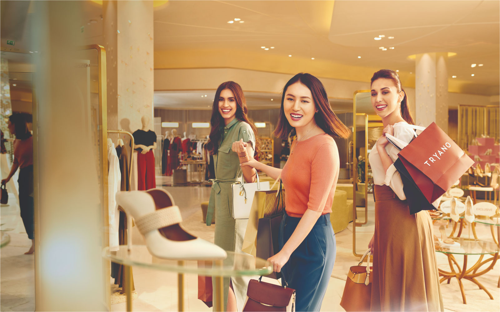 Three women happily shopping at a luxury fashion store in Abu Dhabi.