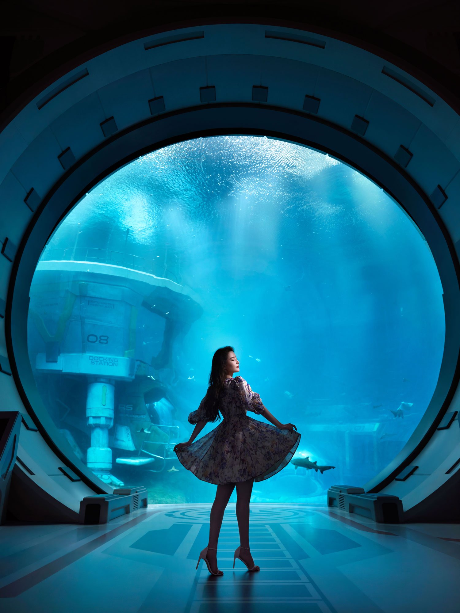 Woman posing gracefully in front of massive aquarium viewing window at SeaWorld Yas Island in Abu Dhabi.