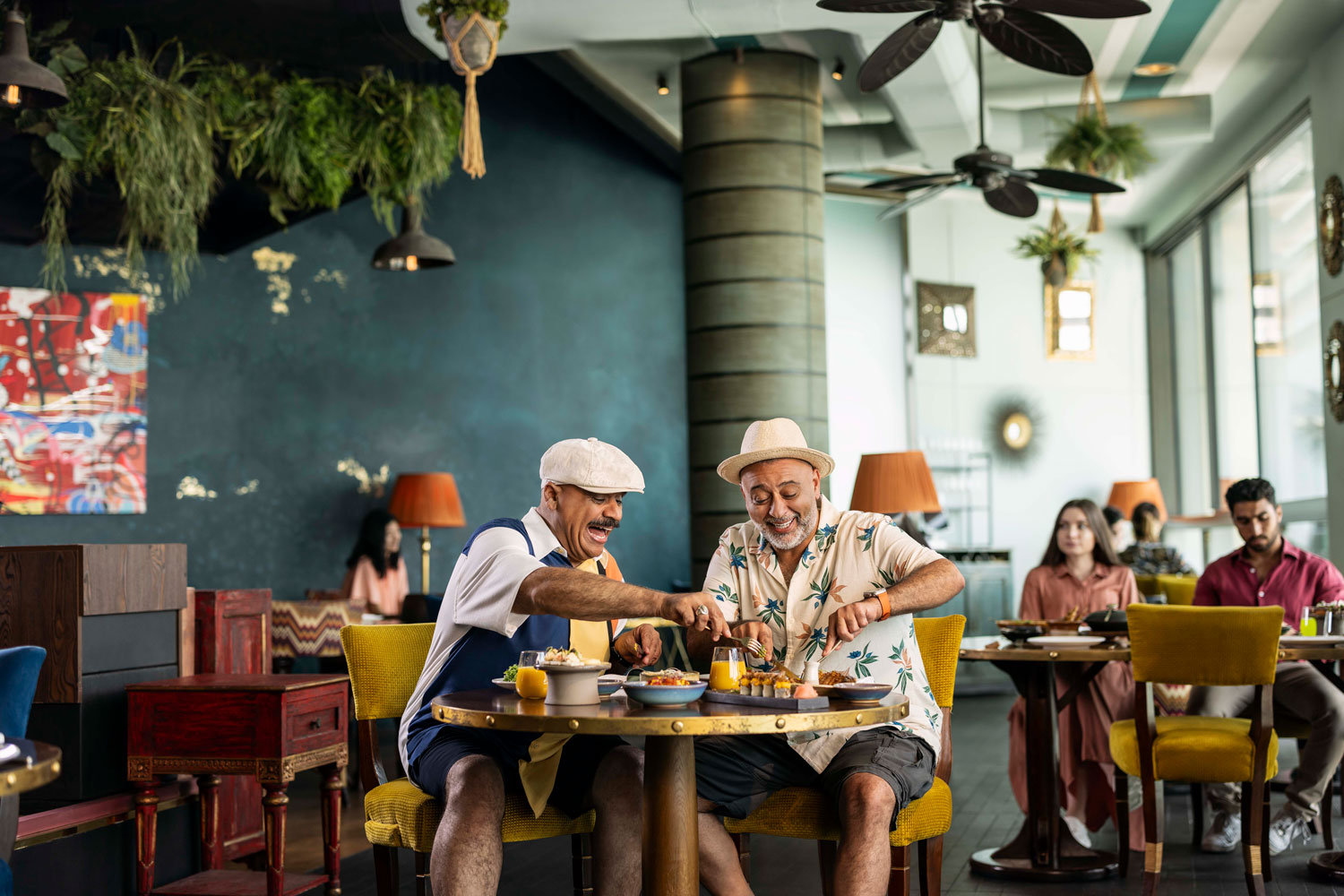 Two men sharing a joyful meal at a vibrant Abu Dhabi restaurant, enjoying local and international cuisine.