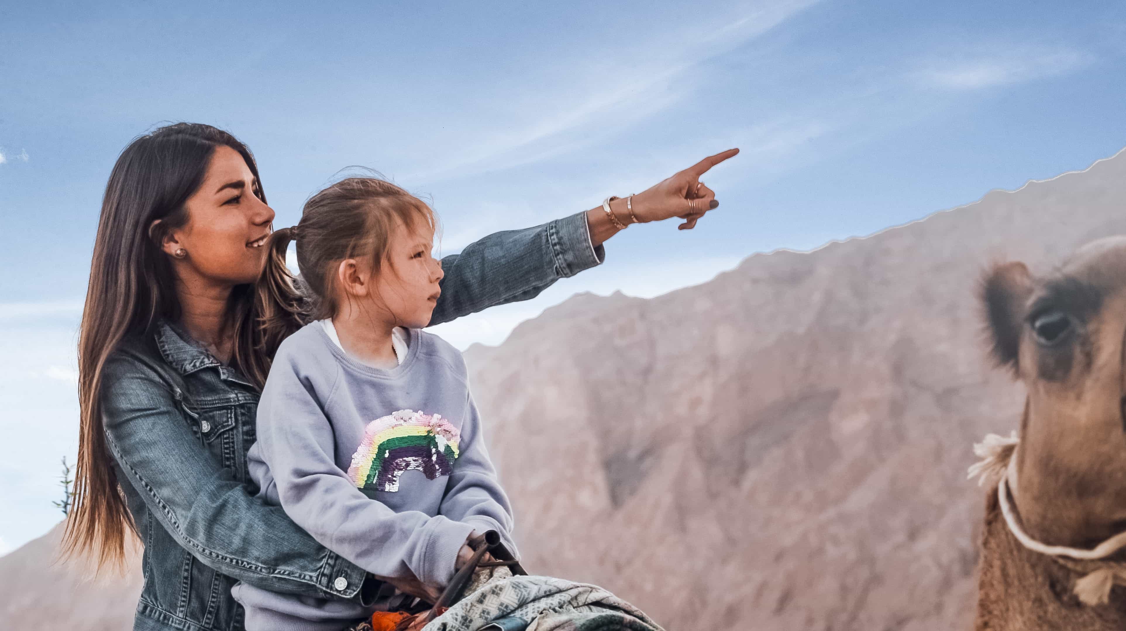 امرأة وفتاة فوق ظهر جمل تشيران إلى جبل حفيت