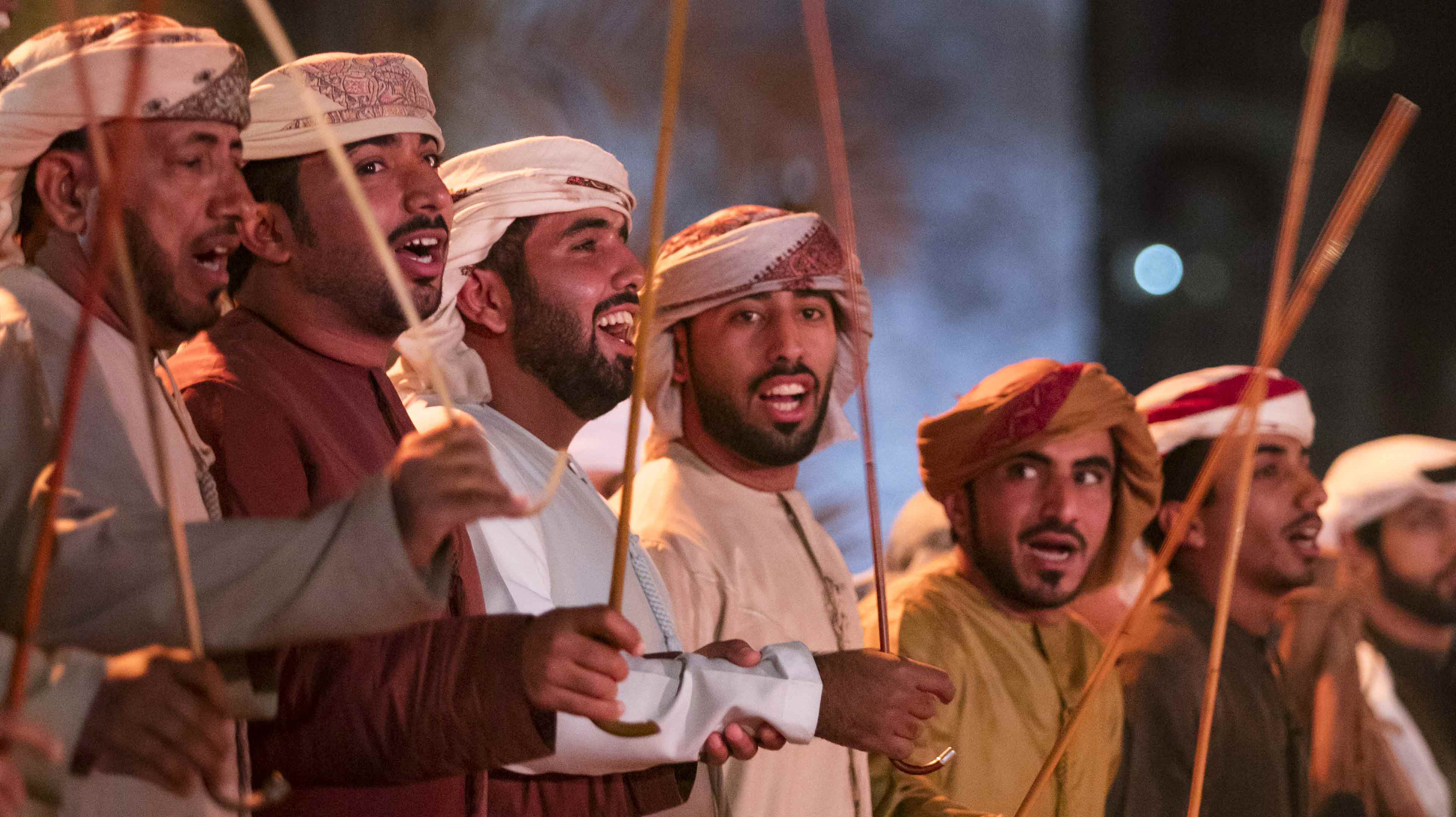 Emirati men holding bamboo sticks and chanting as part of the ayala dance