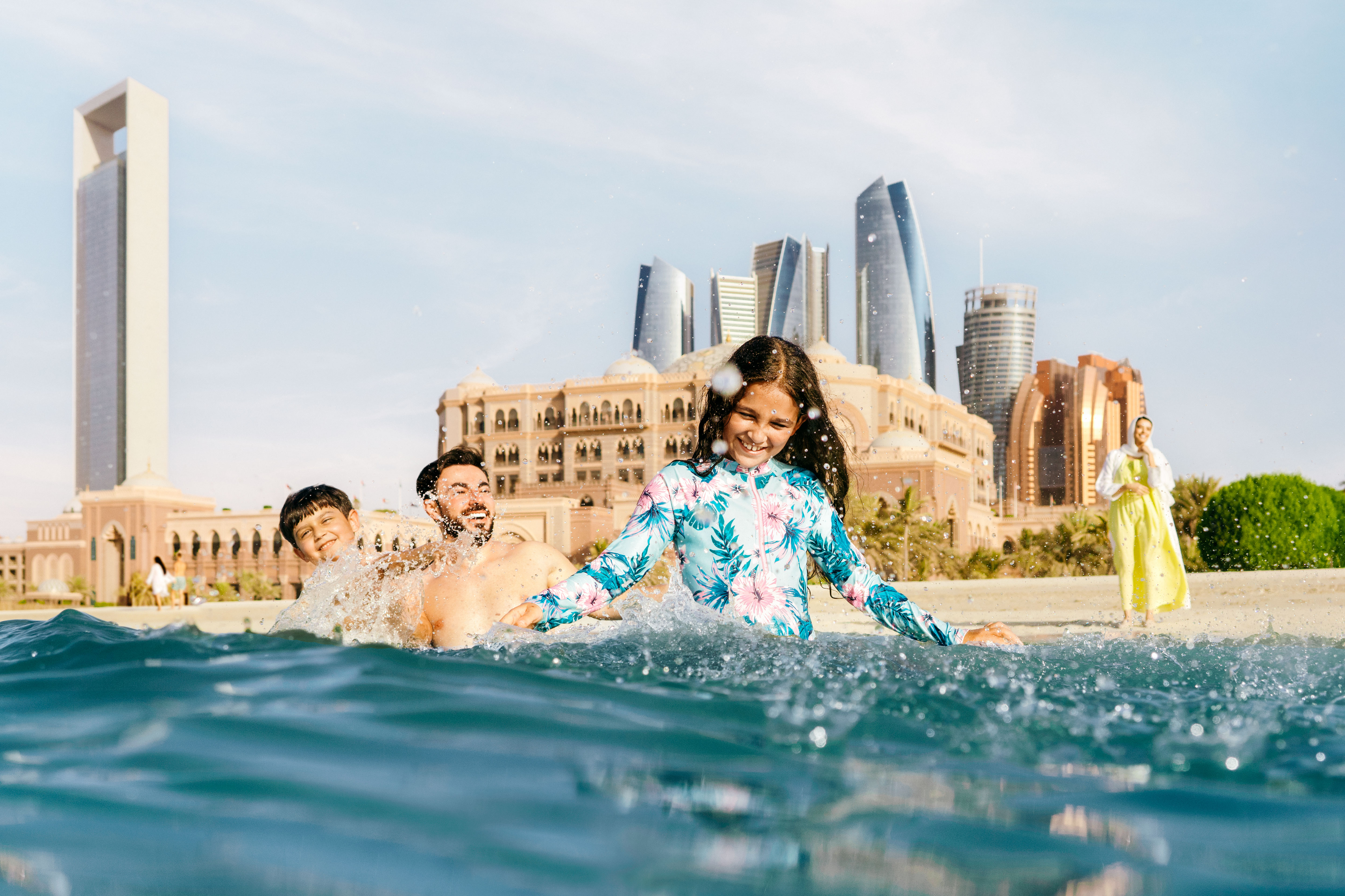 Family of 4 splashing in the Abu Dhabi beach water in the city