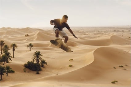 Man in mid-air on a sandboard in the Abu Dhabi dunes, zoomed out