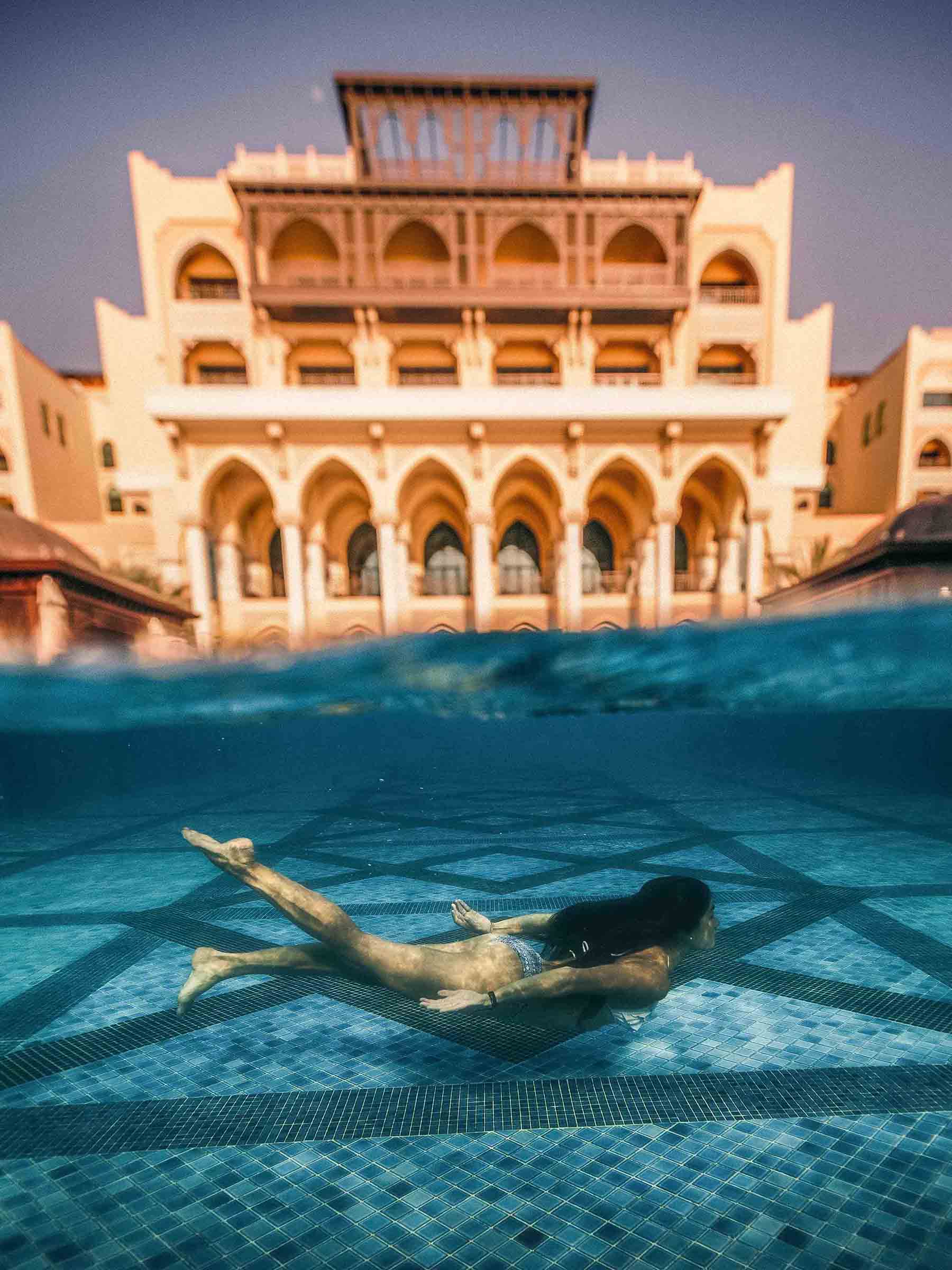 امرأة تستمتع برحلتها إلى أبوظبي في مسبح في الصحراء
