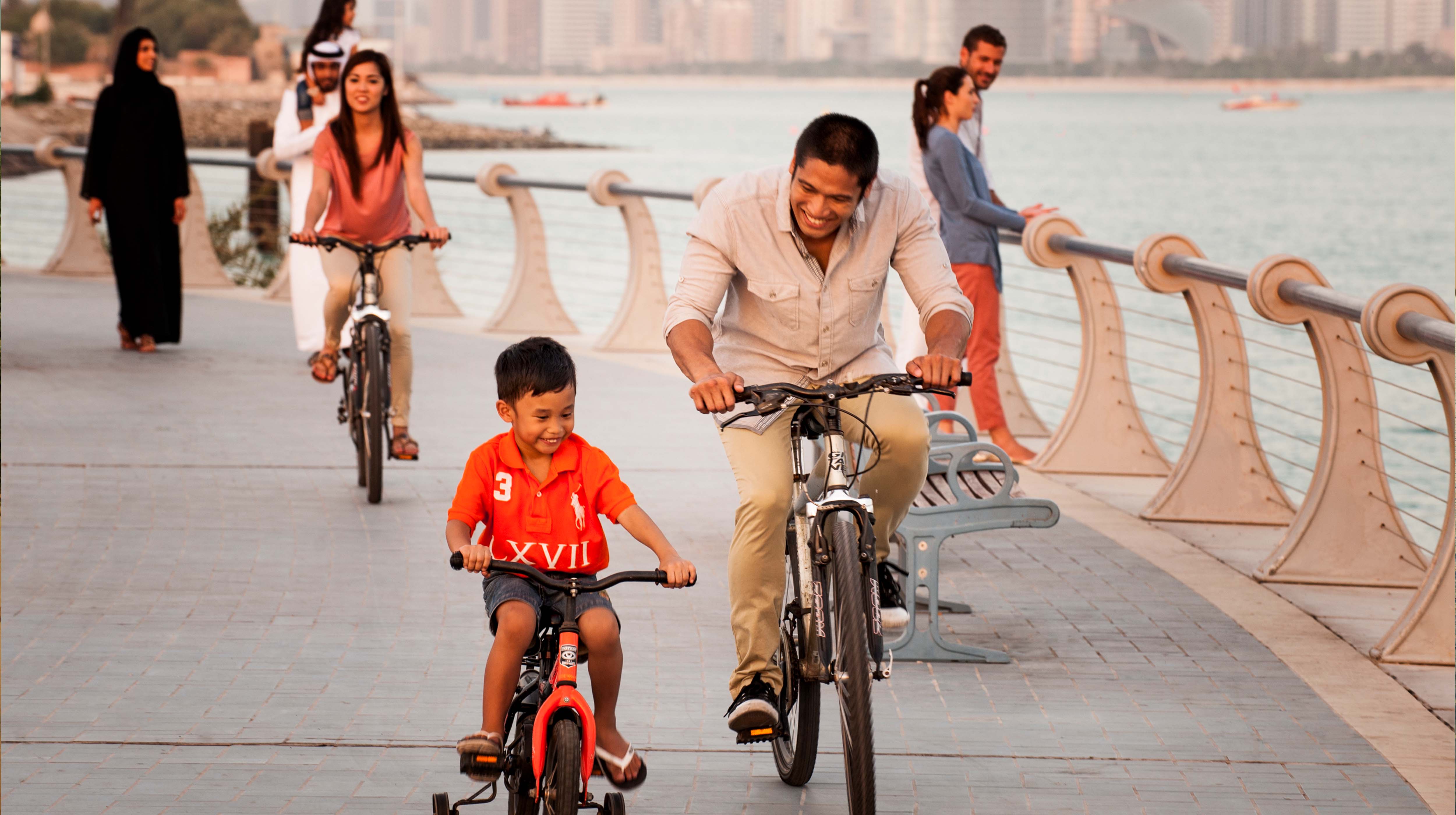 Man and his son enjoying biking on one of the corniche promenades in Abu Dhabi