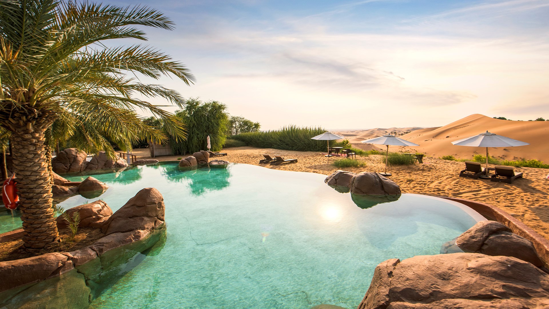  Un paisible coucher de soleil illumine la piscine du Telal Resort, créant une atmosphère sereine dans le désert.