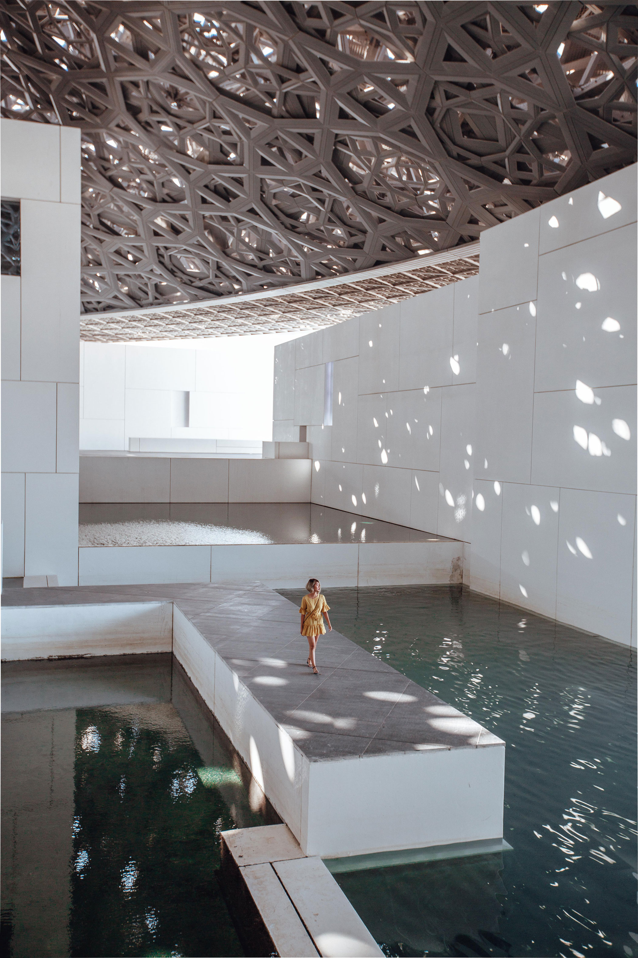 Au Louvre Abu Dhabi, l’ombre du dôme ajouré se mêle à la lumière sur l’eau, évoquant une rencontre subtile entre art, architecture et spiritualité.