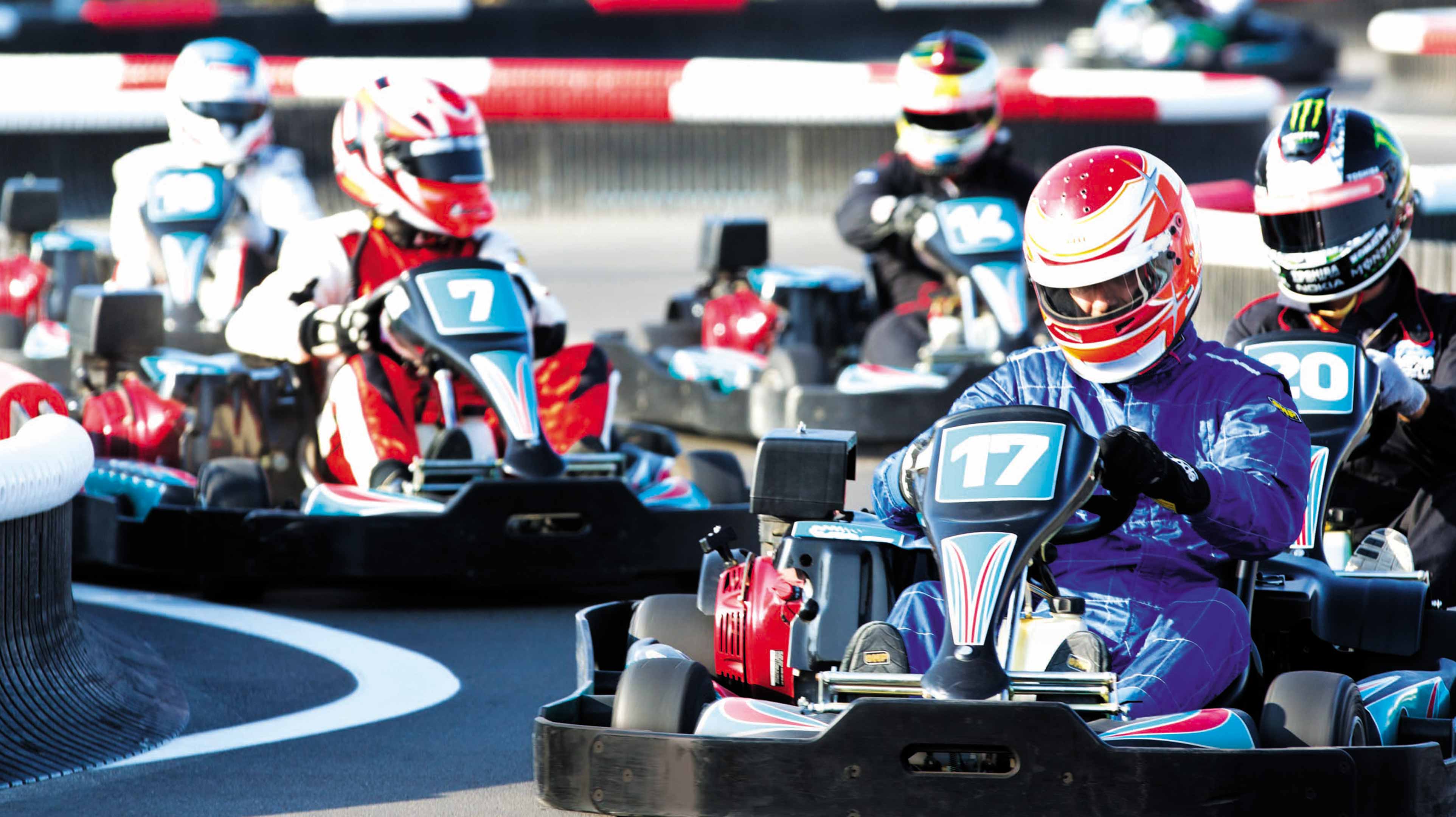 Piloti con tuta e casco si sfidano sulla pista di go-kart Yas Kartzone