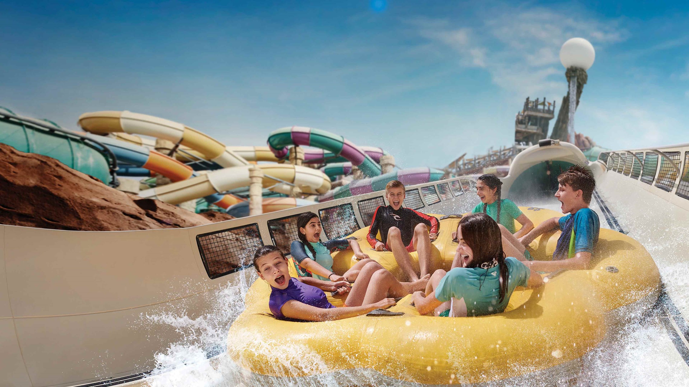 Un gruppo di ragazzi e ragazze in costume da bagno e maglietta si divertono scendendo in canotto giù per gli scivoli del parco acquatico Yas Waterworld