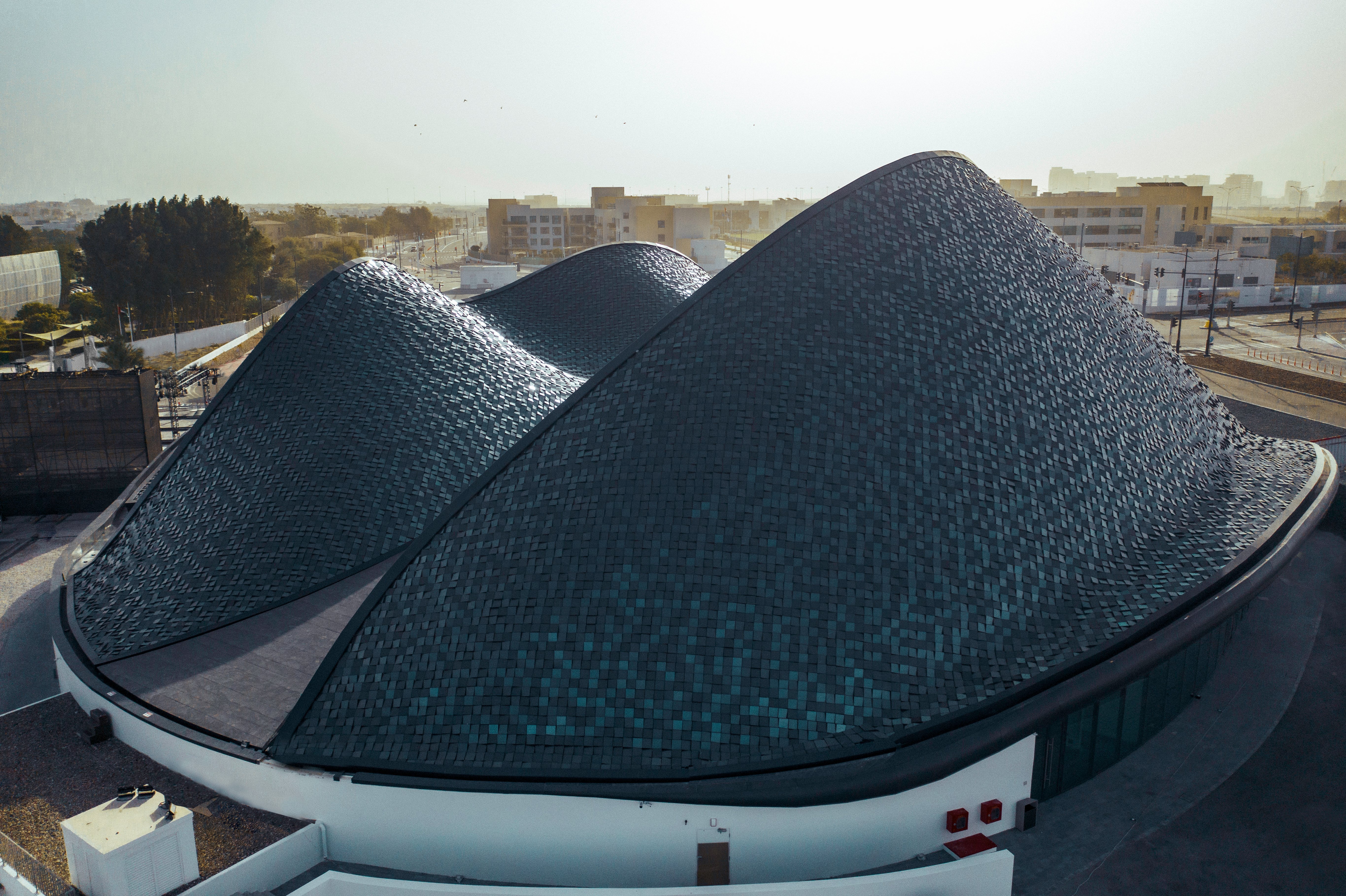  Un bâtiment moderne aux formes organiques, symbolisant l'innovation d'Abu Dhabi, se dresse magnifiquement sous le ciel clair.