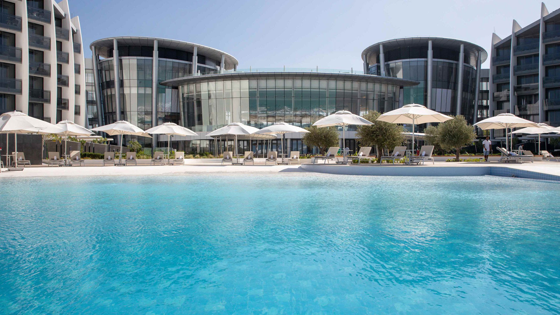 Infinity-Pool im Jumeirah Saadiyat Resort mit Blick auf ein modernes Glasgebäude