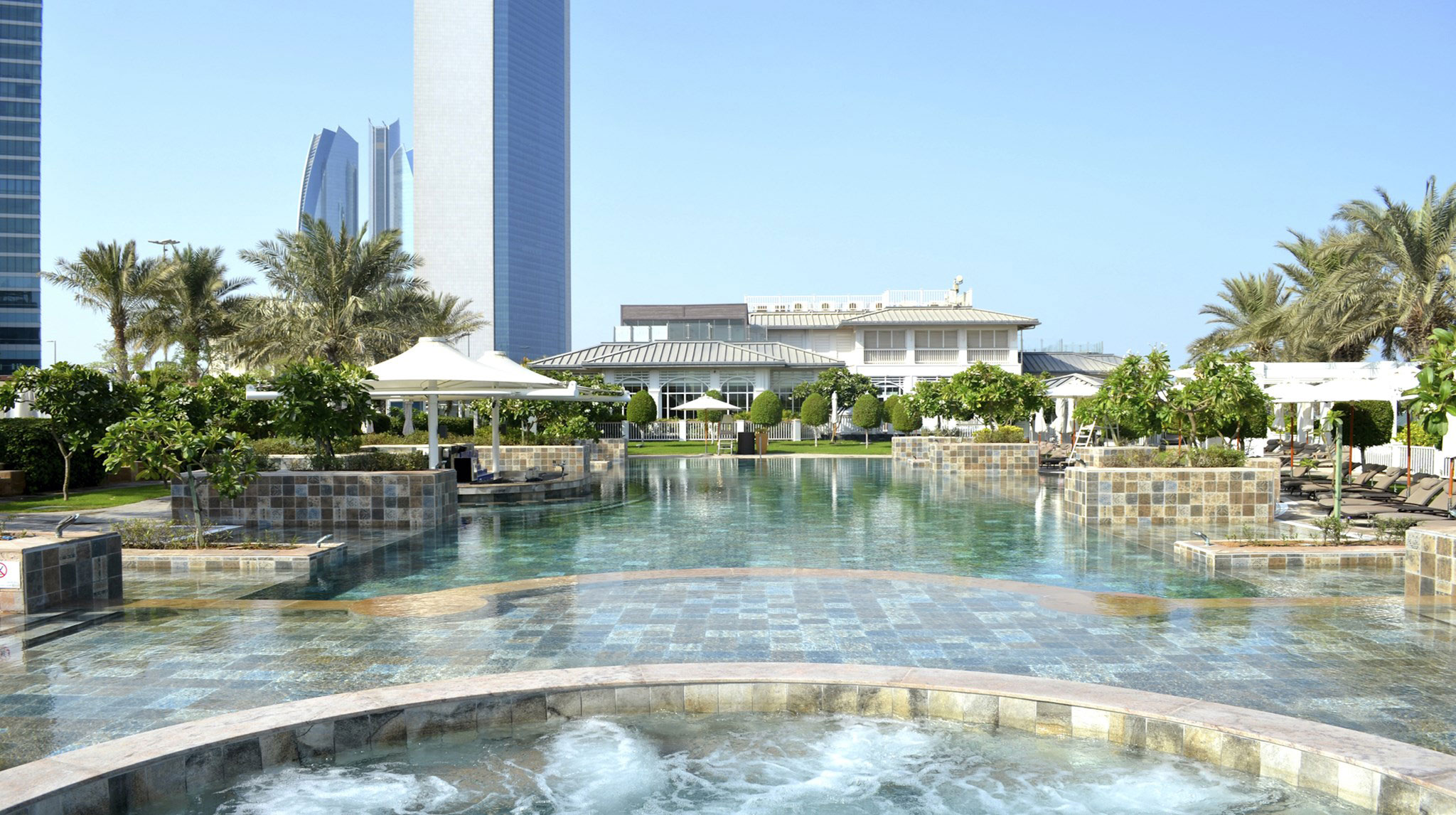 Entspannungsbereich am Pool des St. Regis Abu Dhabi mit Blick auf Palmen