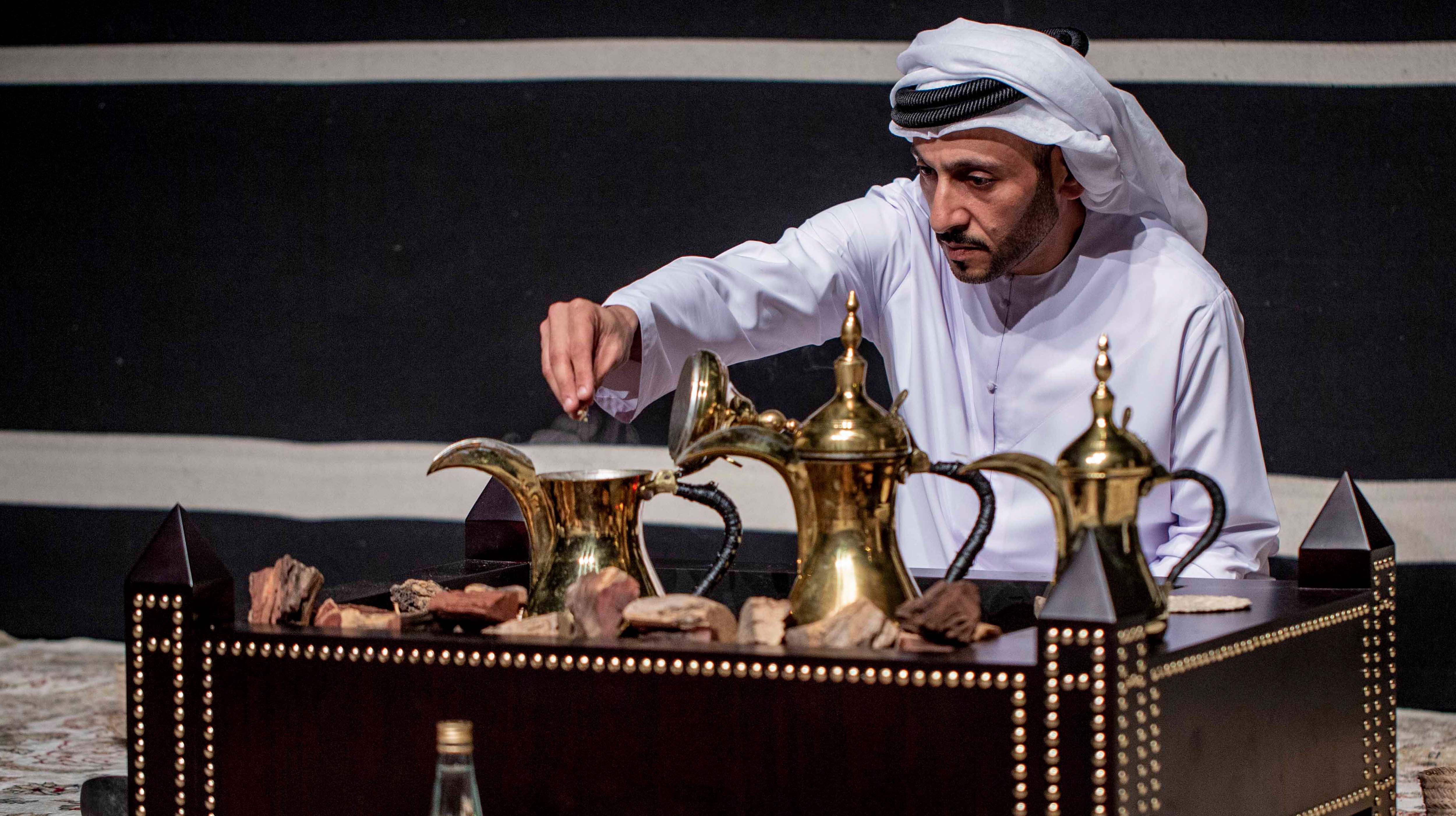Uomo in abiti tradizionali prepara il tipico caffè arabo con le tradizionali caffattiere mediorientali
