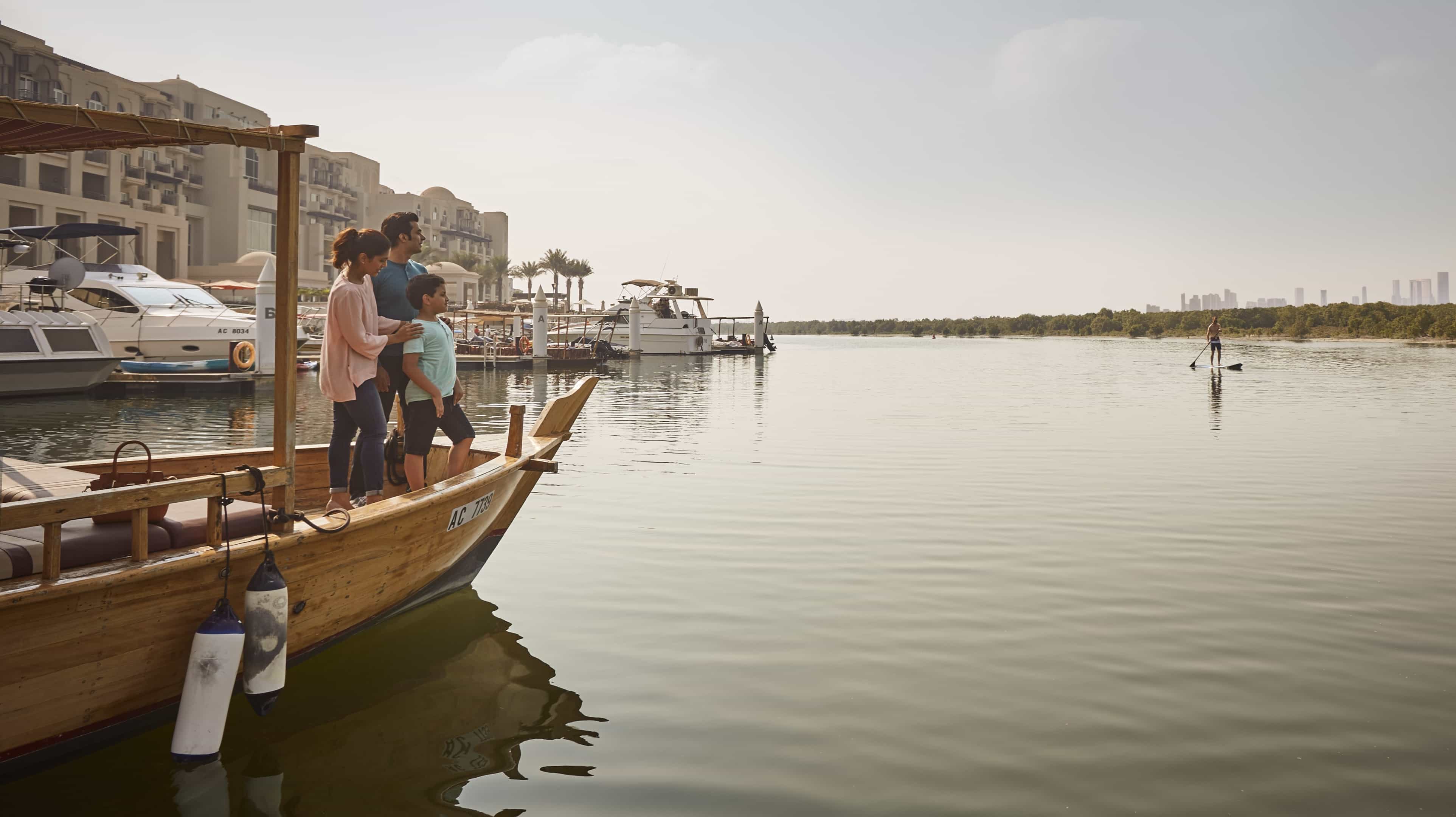 Indian family standing in a dhow in the waters of Abu Dhabi Emirate