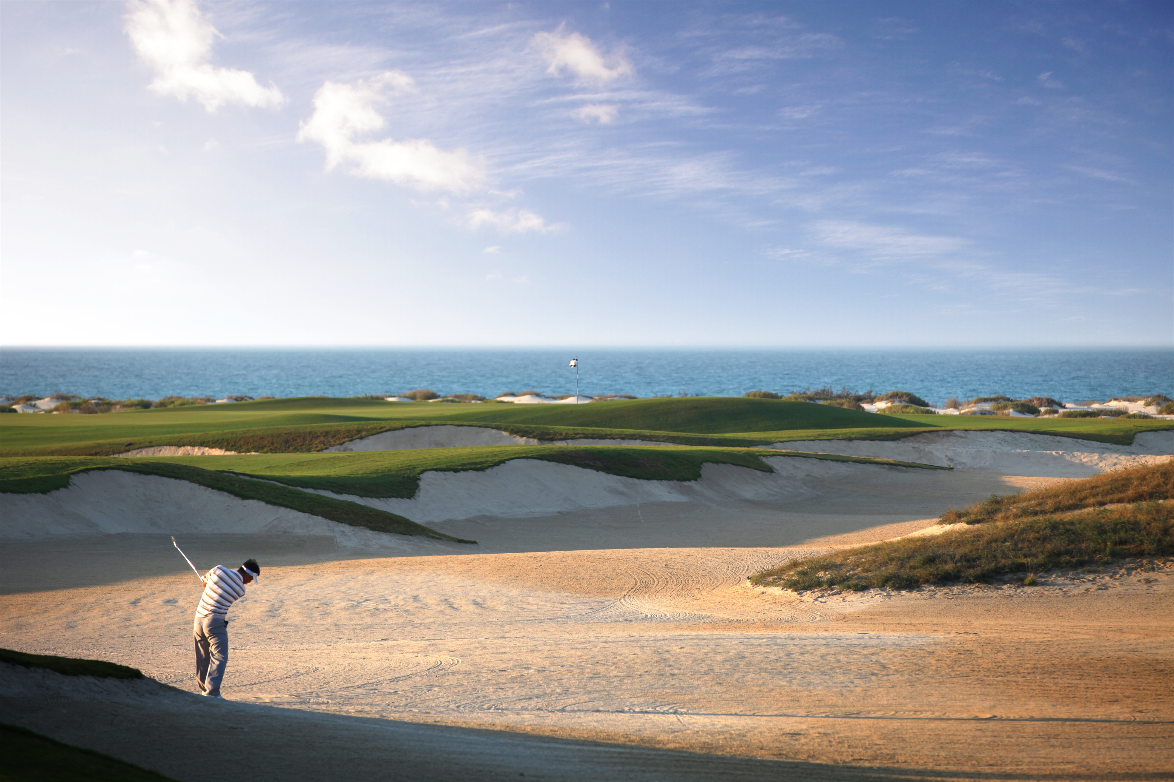  Sur le green d'un golf d'Abu Dhabi, un joueur savoure l'instant. Une expérience de voyage luxe à proximité du club de golf de Saadiyat Beach.