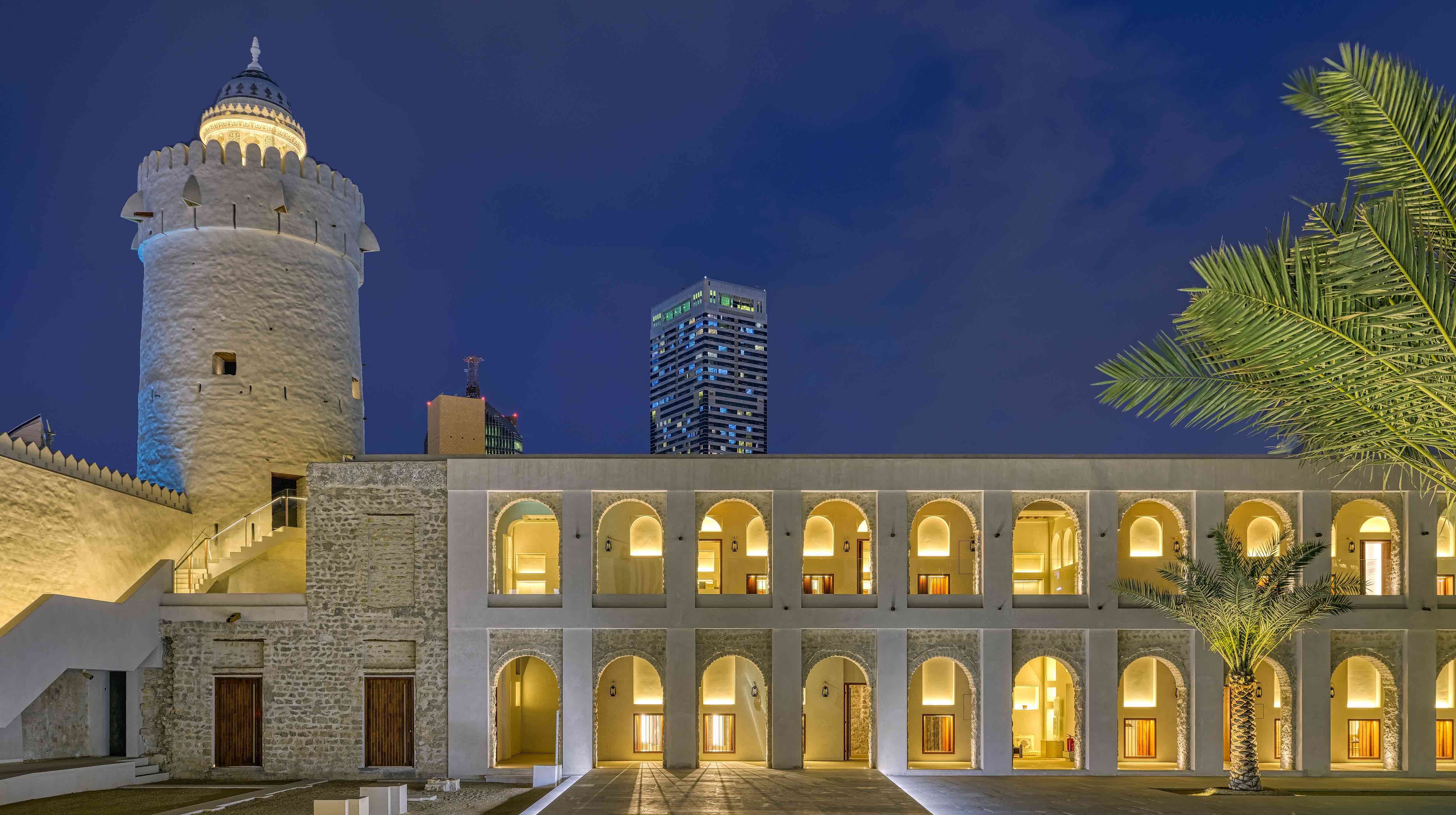 Visione notturna dell'antica struttura di Qasr Al Hosn con i due piani di archi e la torretta illuminati