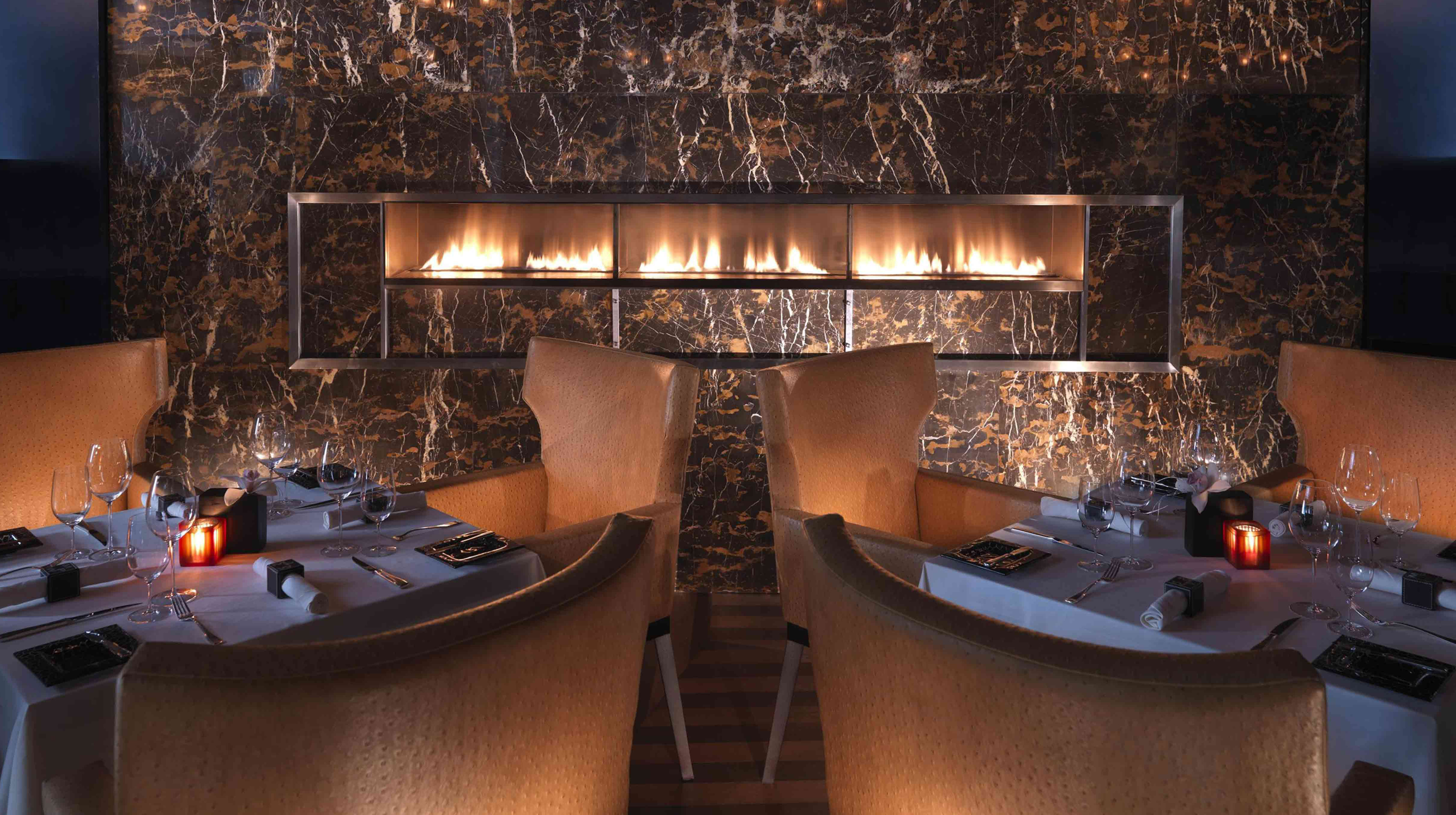 Dining tables in front of a fireplace at Marco Pierre White Steakhouse & Grill