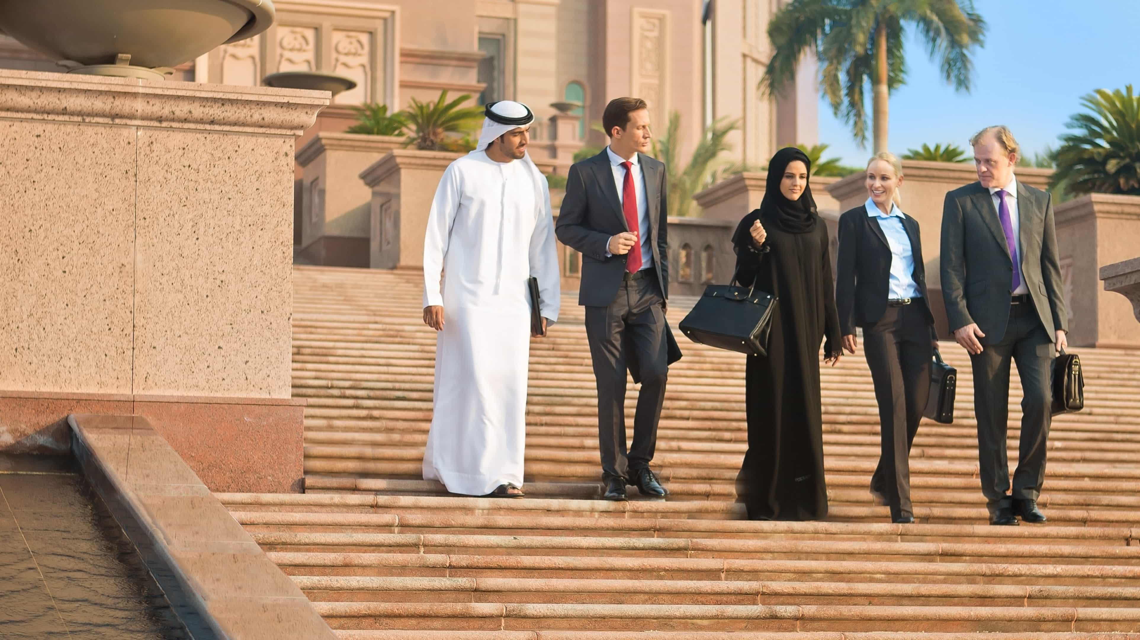 A group of diverse business people walking down the steps of Emirates Palace