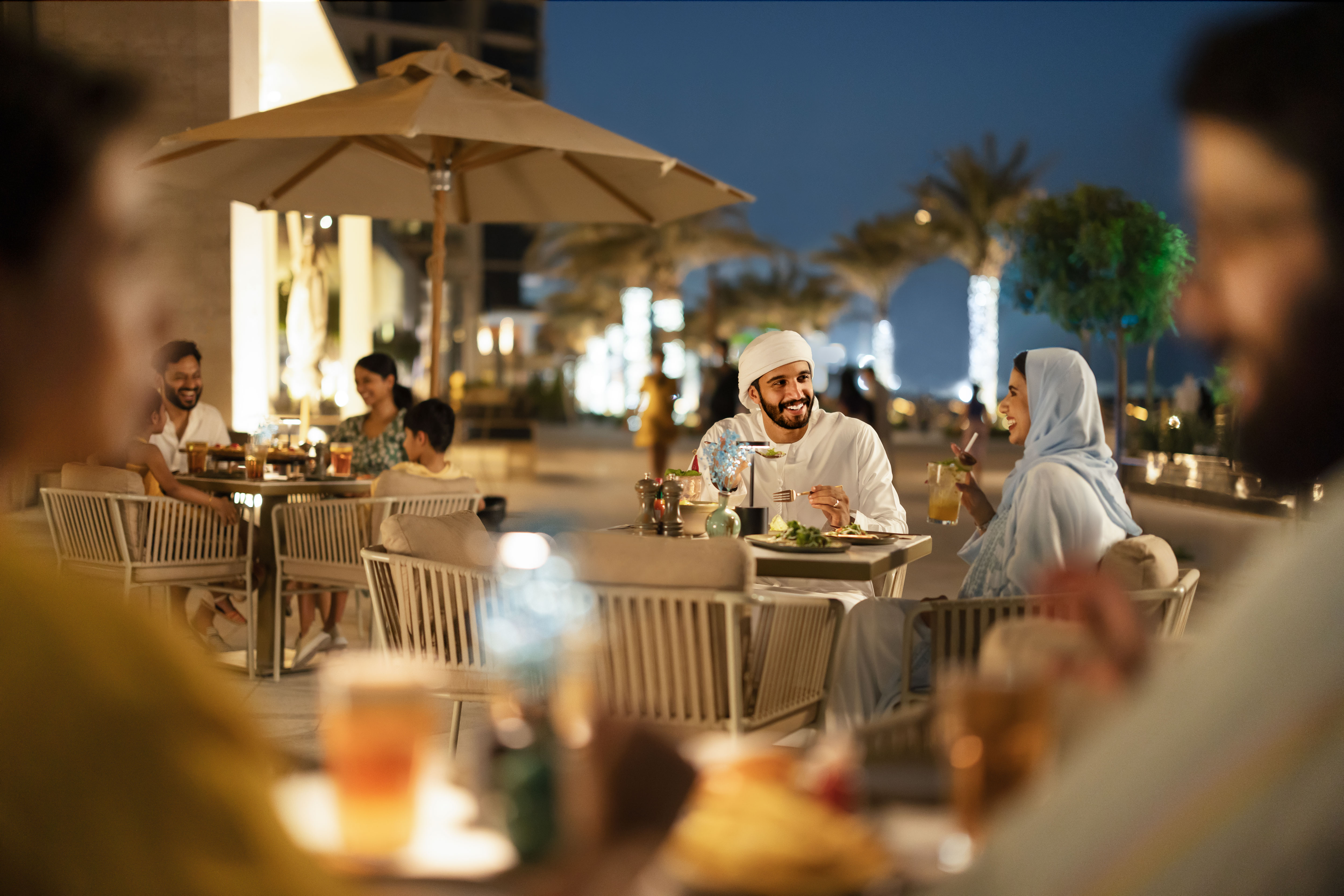 Arabic couple smiling and talking at an Abu Dhabi restaurant, outside at night