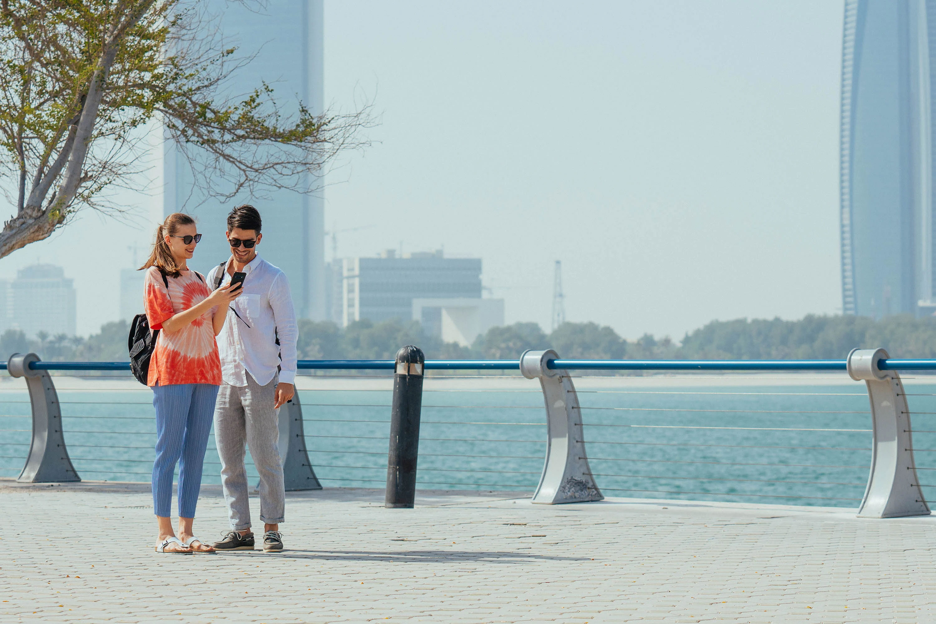 Western couple looking at a phone near the sea in Abu Dhabi