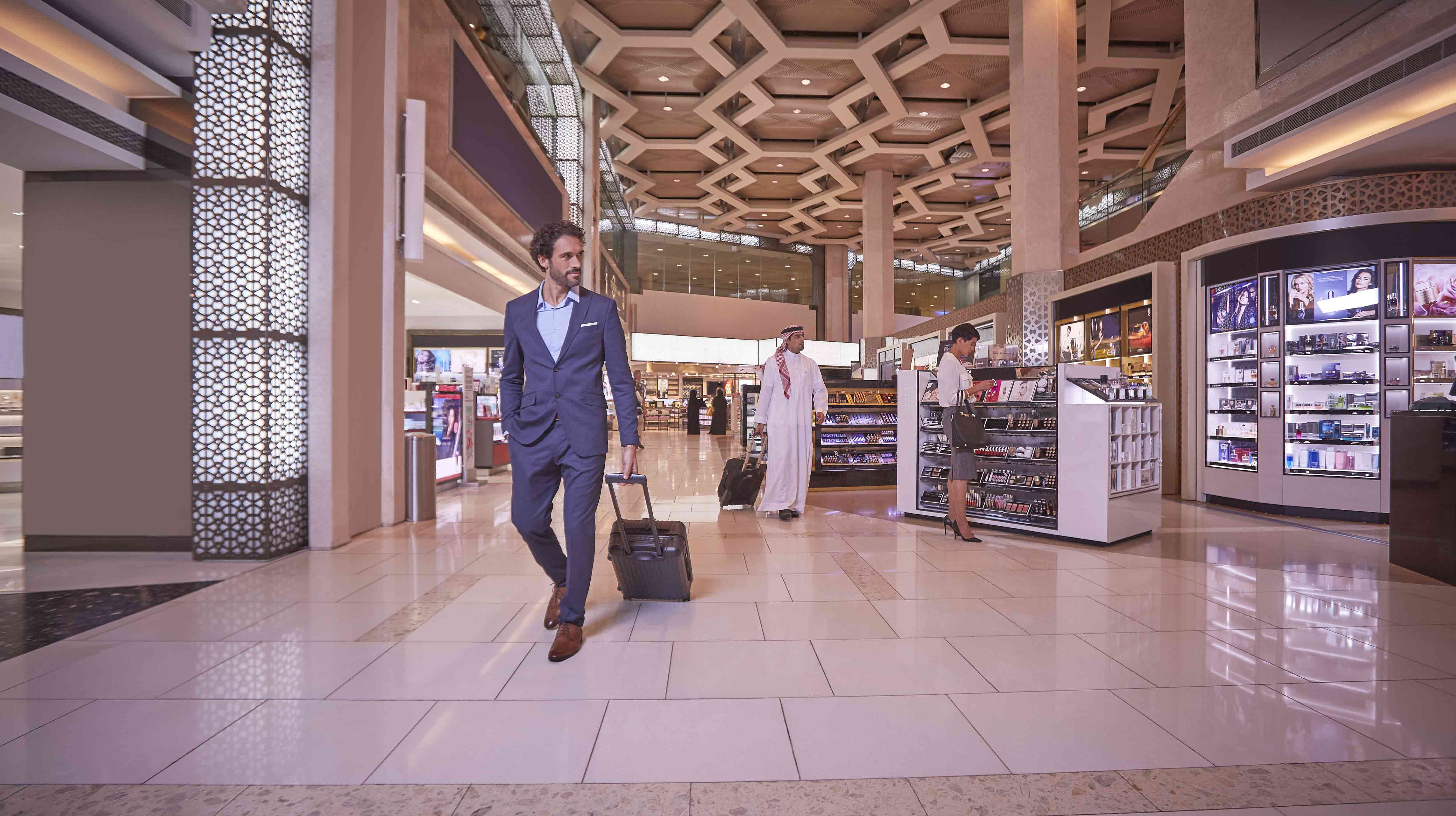 Ein Geschäftsmann mit einem Koffer schlendert durch den Duty Free am Flughafen Abu Dhabi