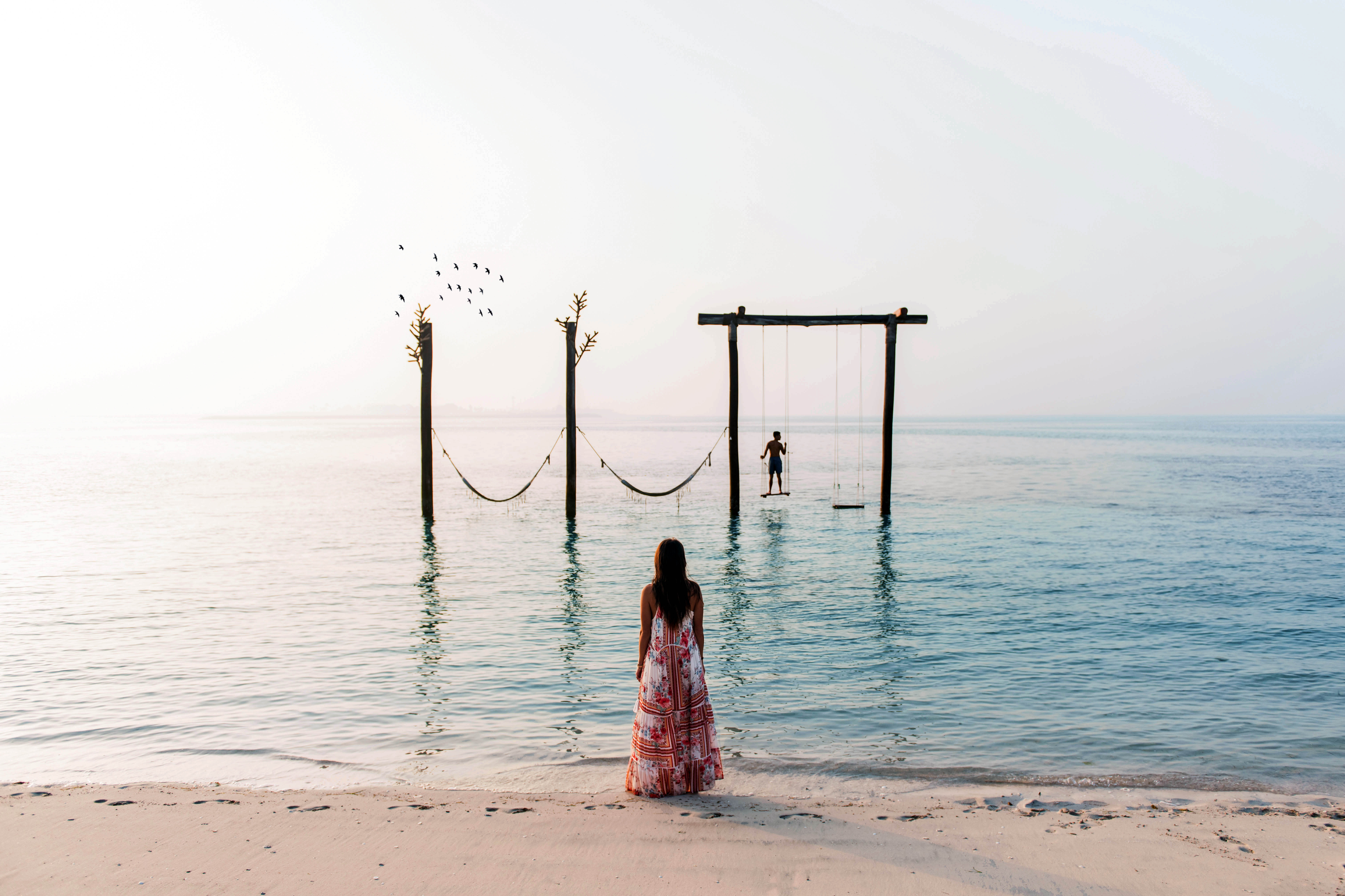 Woman standing at the beach shore in Abu Dhabi watching husband on beach swing
