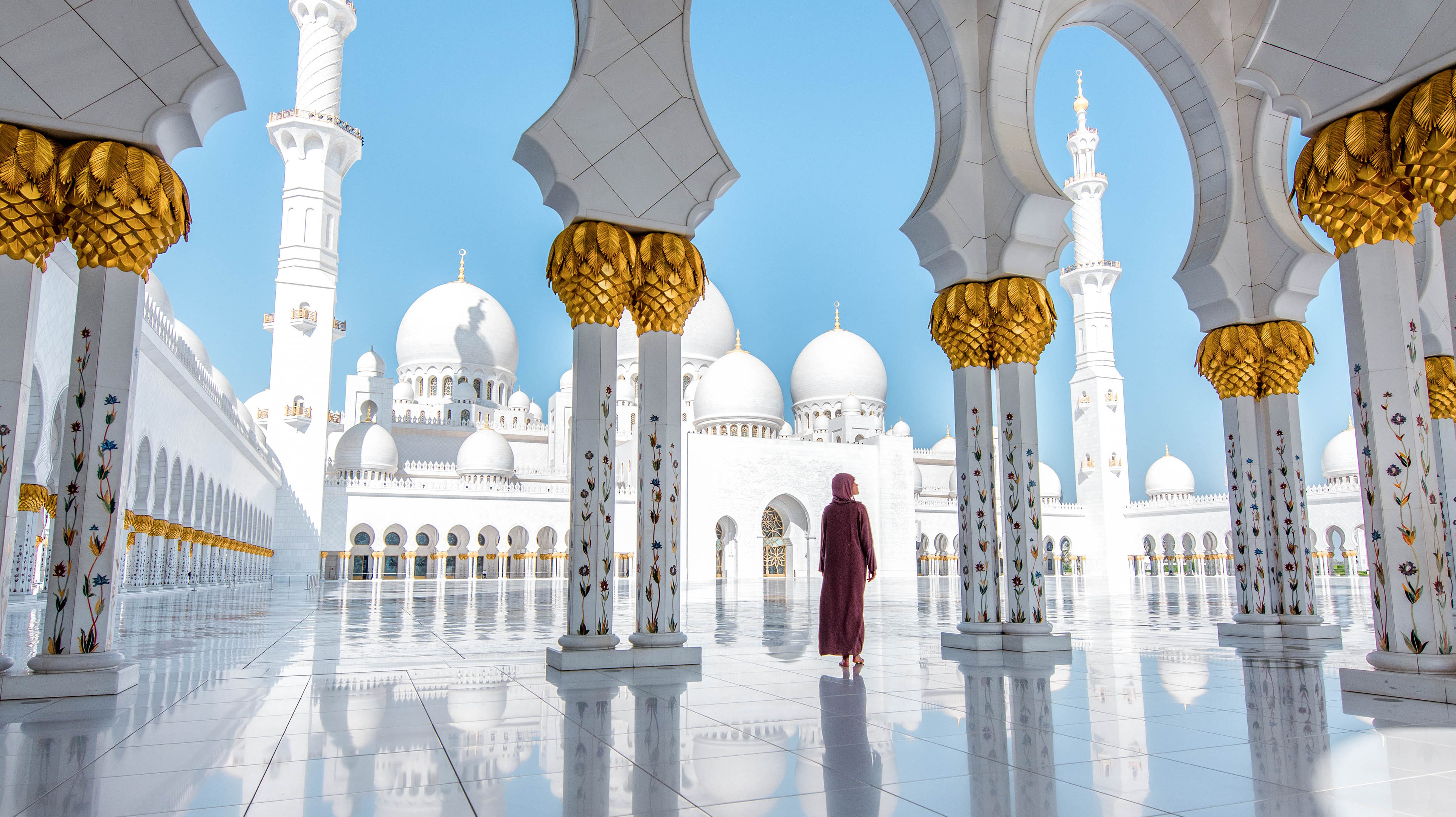 Woman walking in Sheikh ZayedGrand Mosque, experiencing peace and grandeur