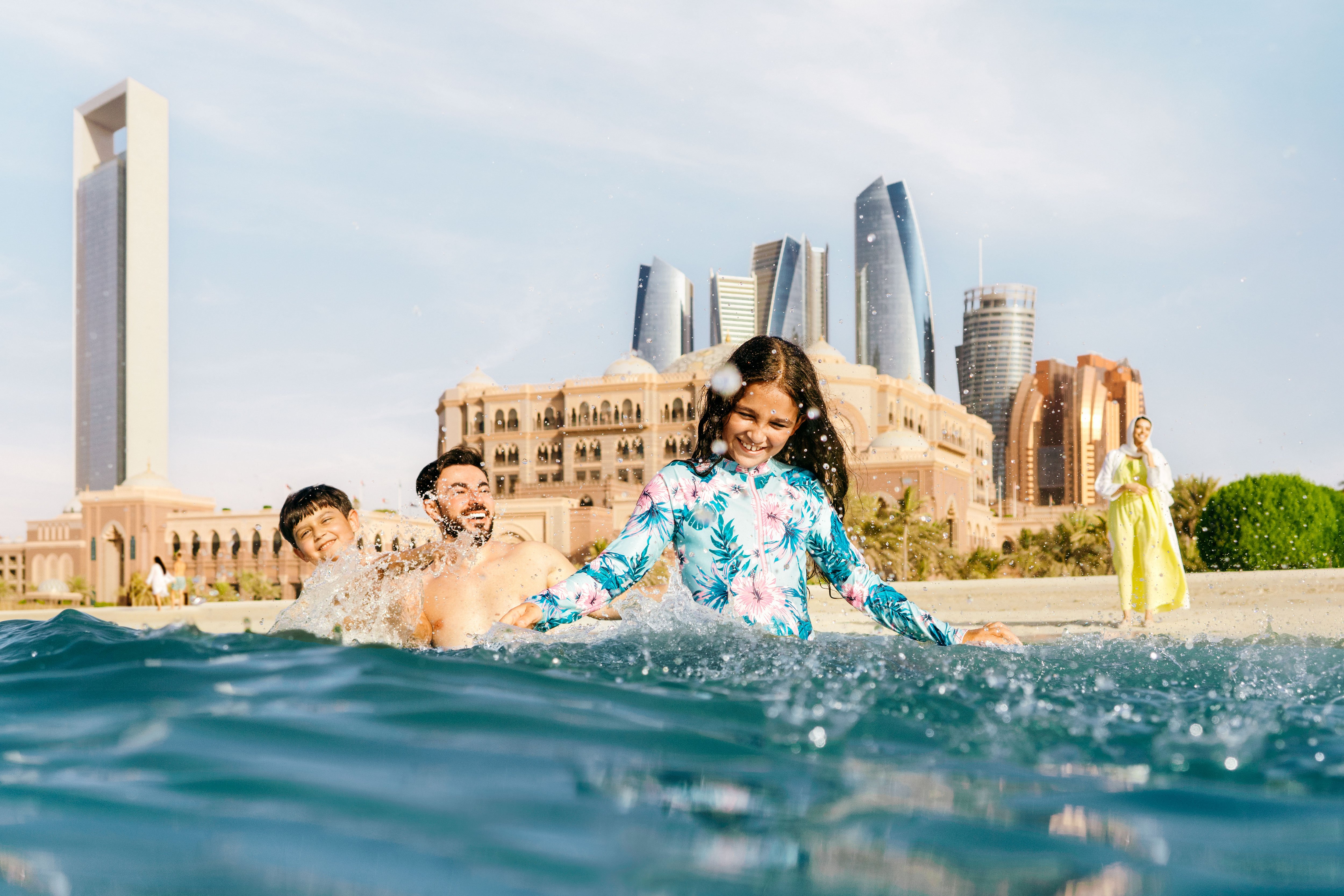 عائلة من أربع أفراد تتمتع باللعب في مياه إحدى شواطئ أبوظبي قرب قصر الإمارات