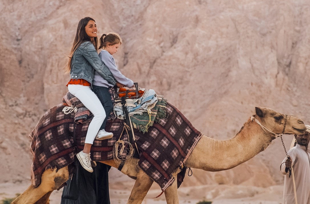 Woman and girl on a camel's back near Jebel Hafit Tombs