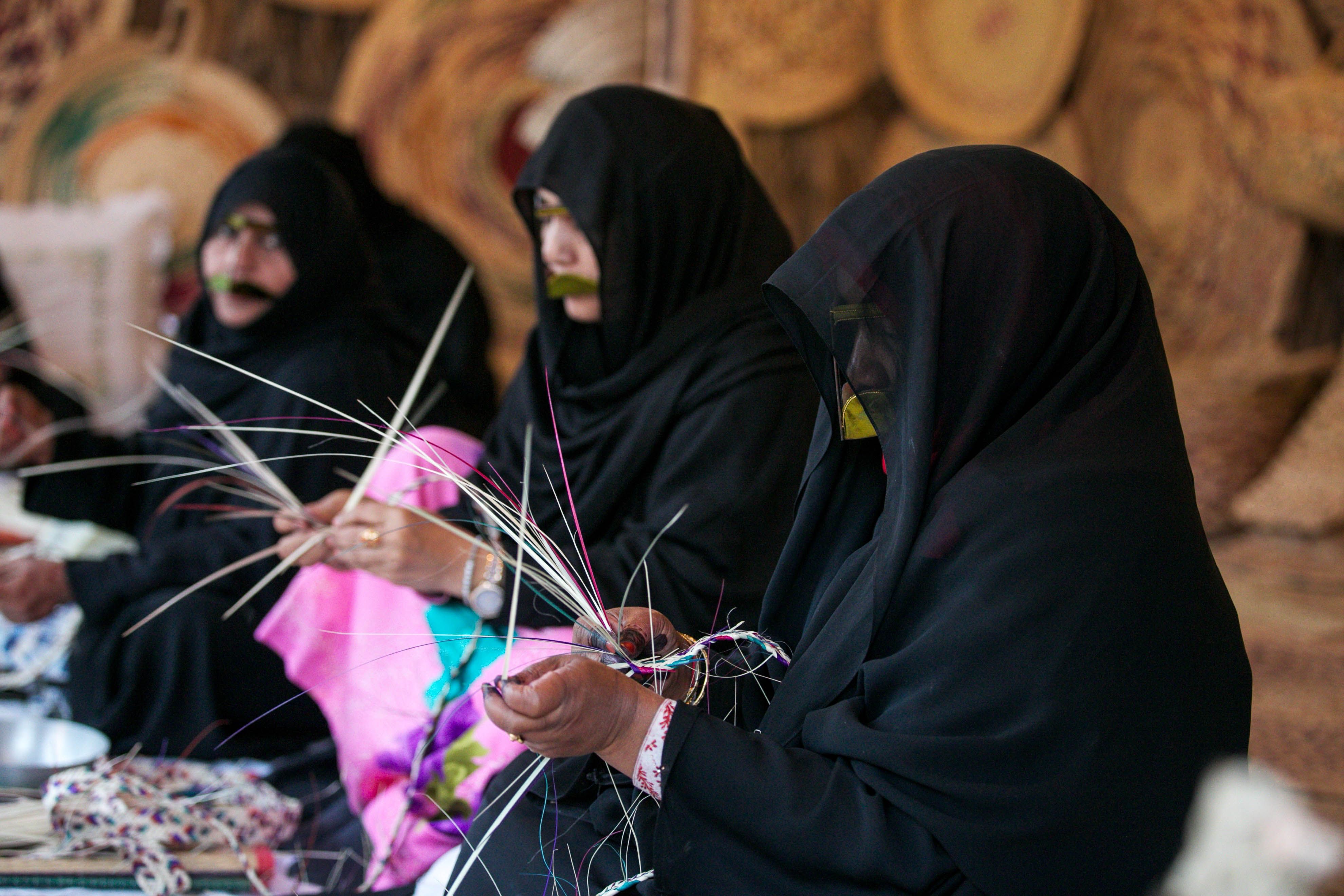  Des femmes vêtues d’habits traditionnels pratiquent l'artisanat typique, le sadu