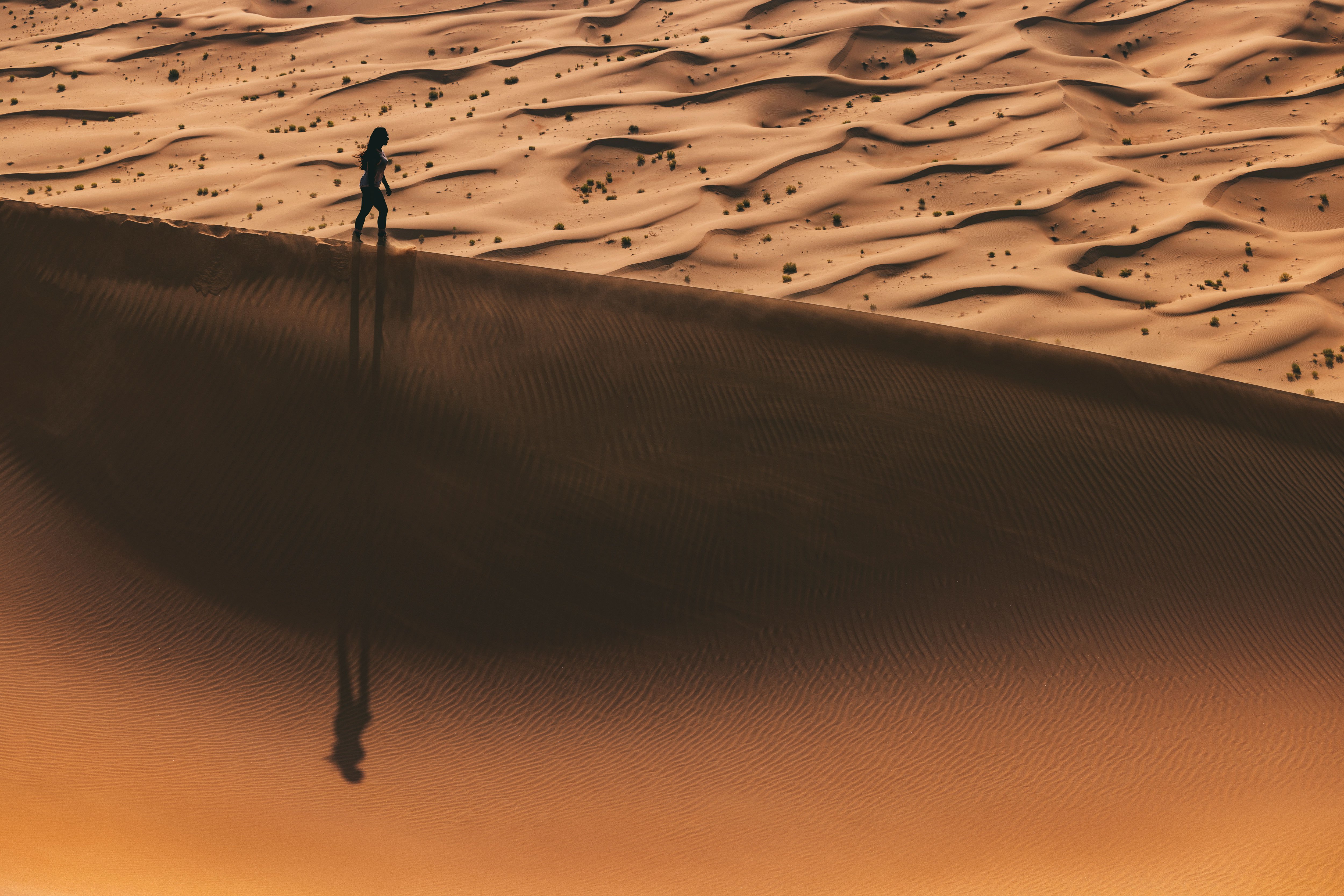 Woman walking in the middle of sand dunes in the Abu Dhabi desert