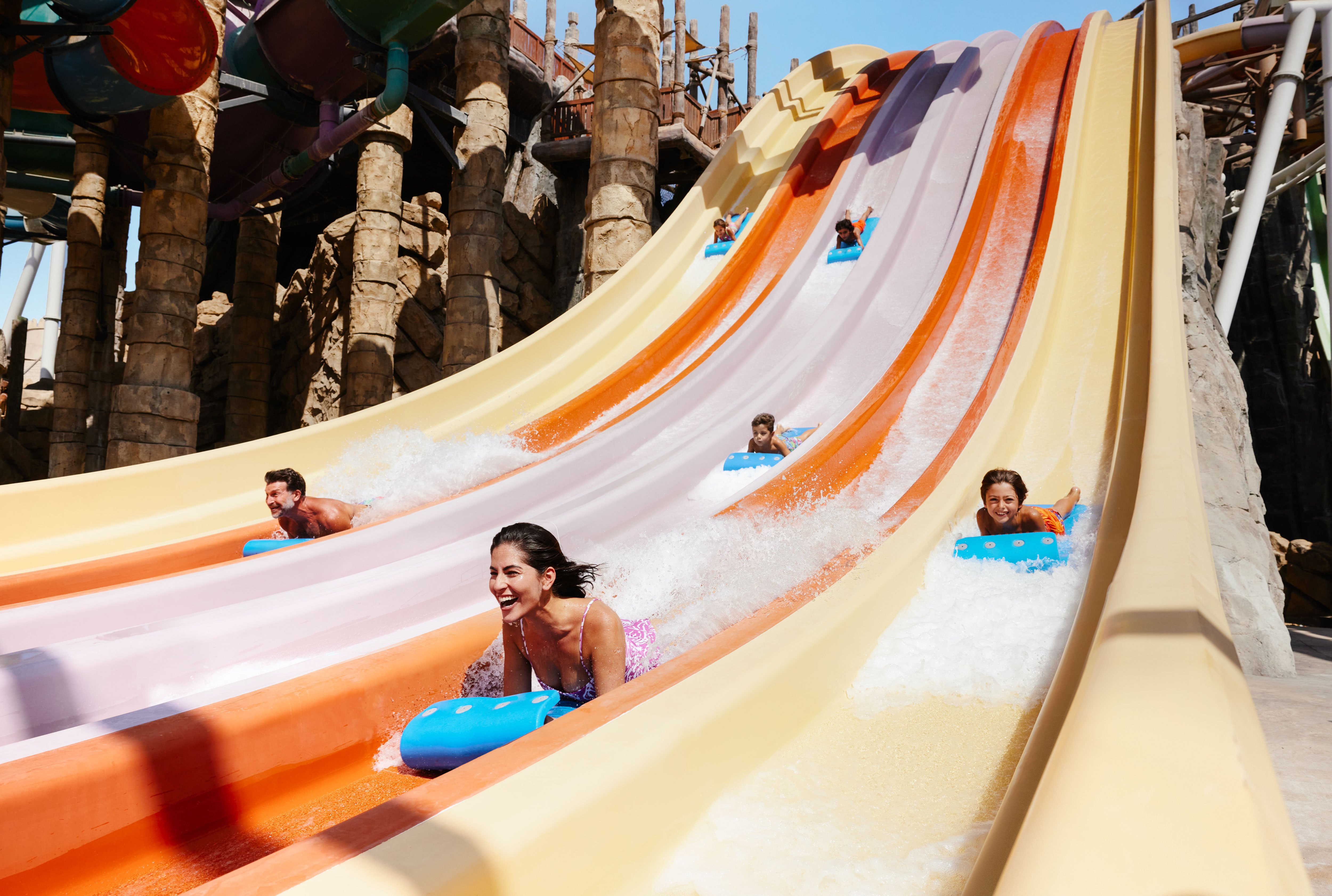 Western family sliding on tubes down a blue Yas Waterworld slide