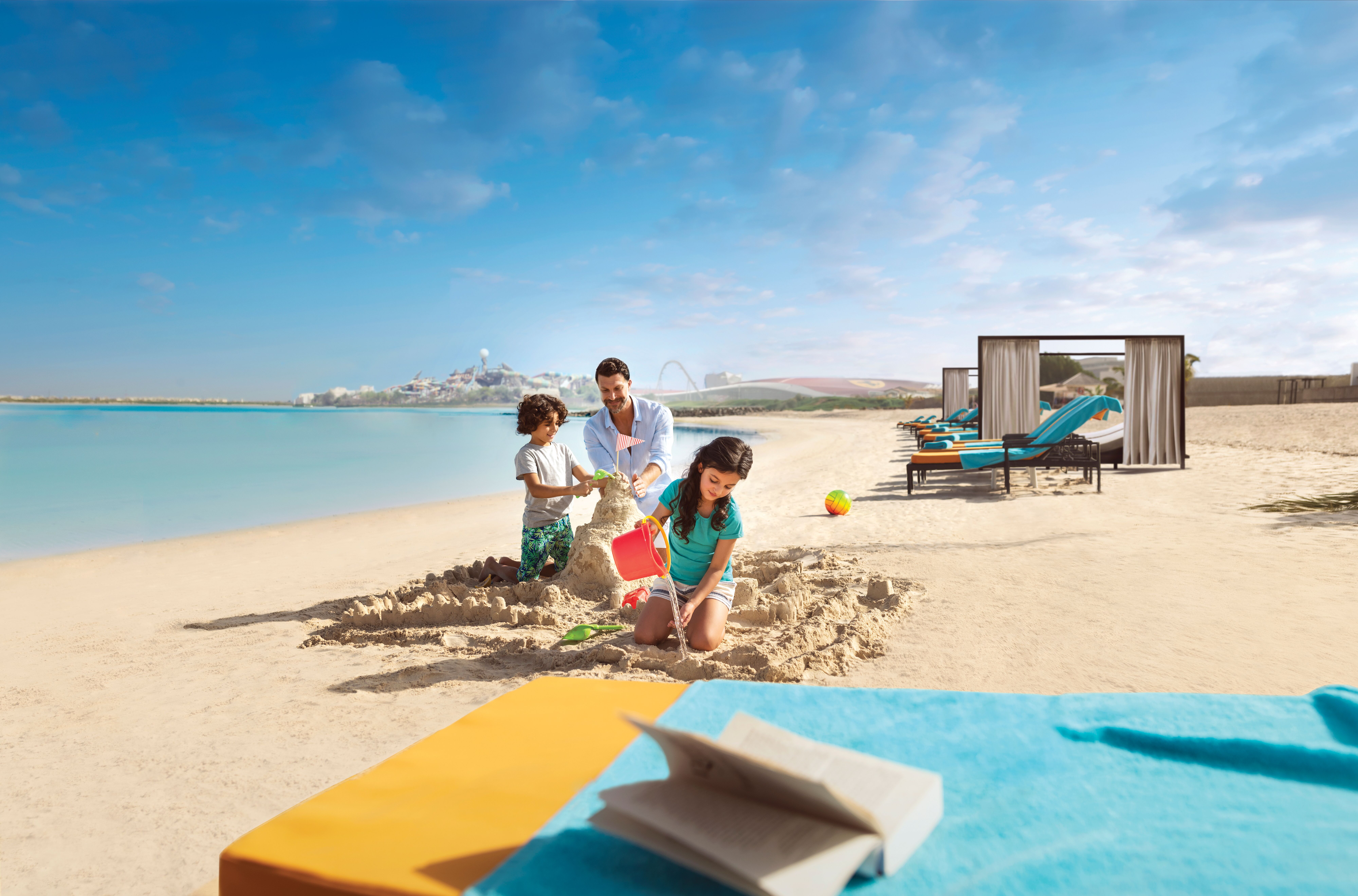 أب مع طفلين يلعبون بالرمال في شاطئ ياس