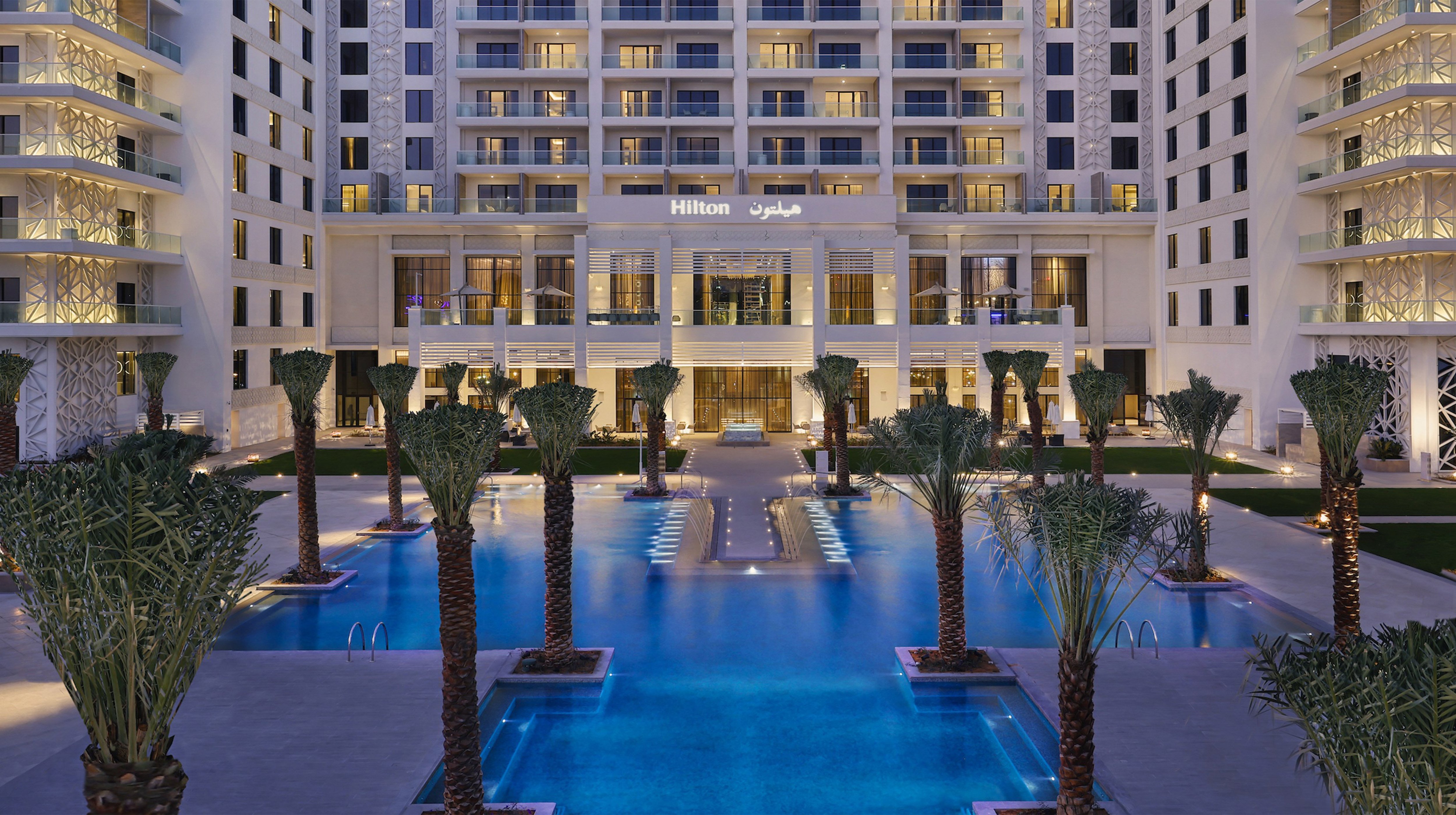 Vista frontale della piscina con palme dell'Hilton Abu Dhabi sul lungomare di Yas Bay Waterfront